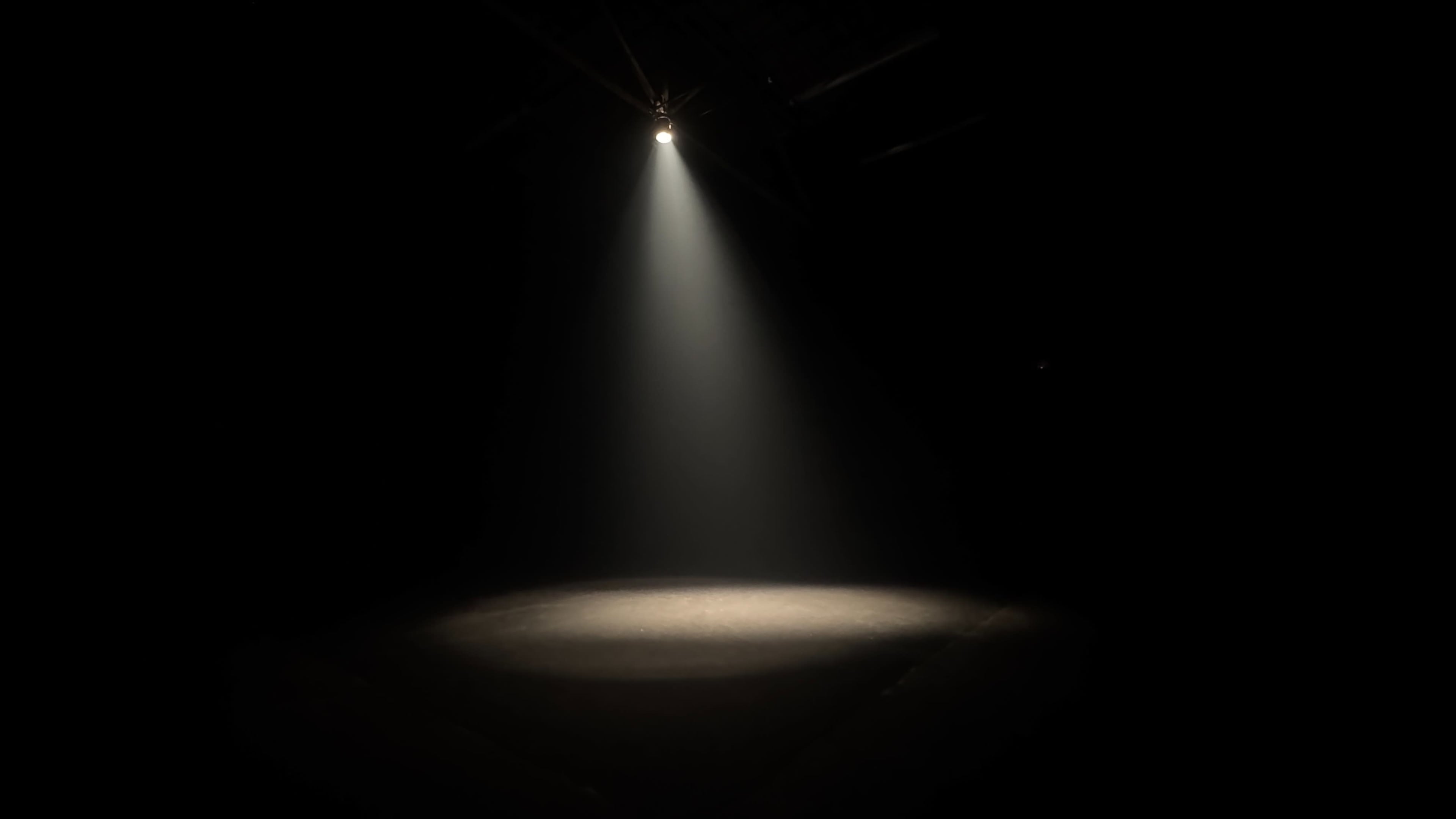 A spotlight shines down on a small circular area of a dimly lit stage.