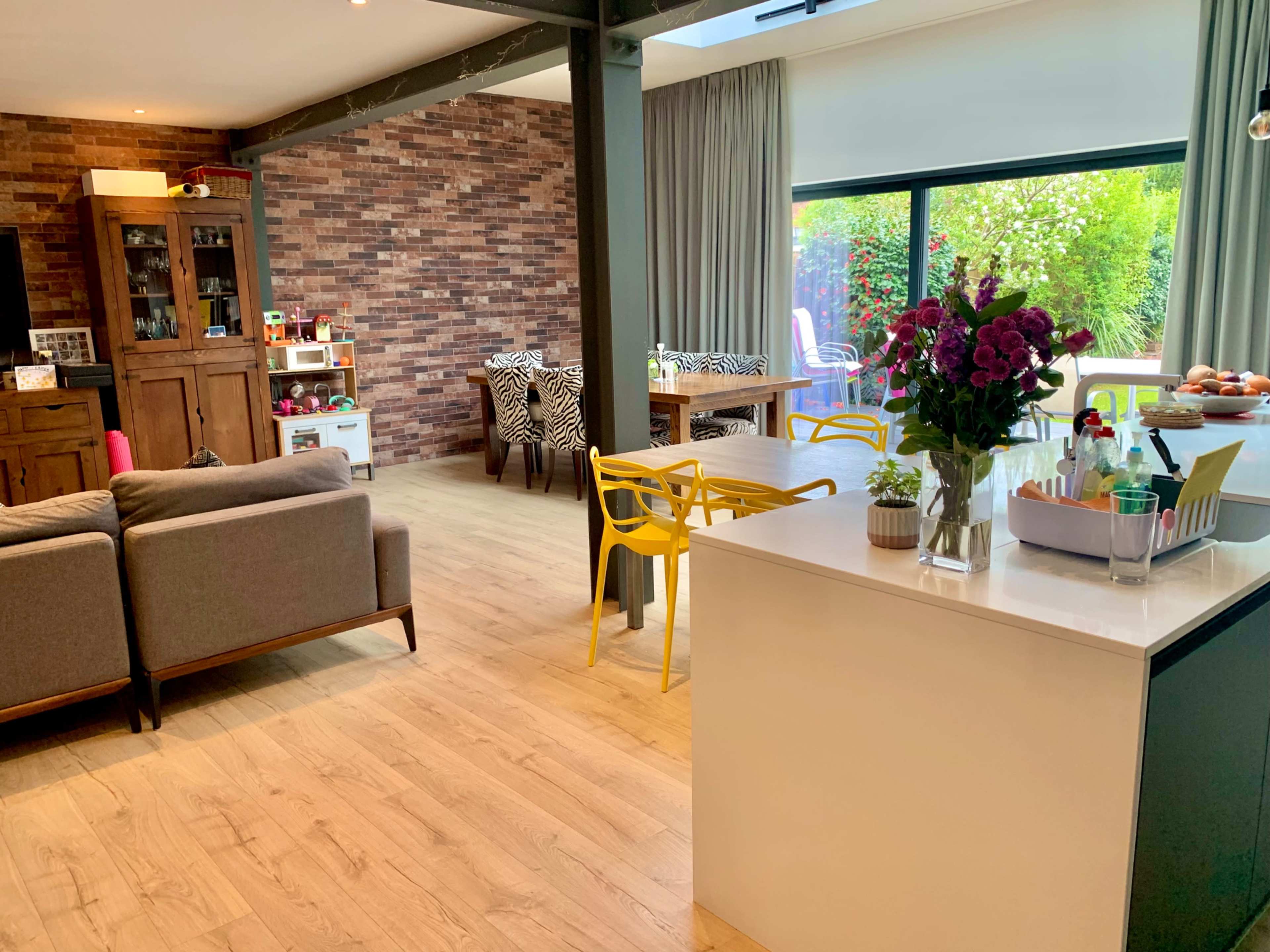 A modern open-concept living space features a kitchen island, dining area with patterned chairs, and a cozy seating arrangement.