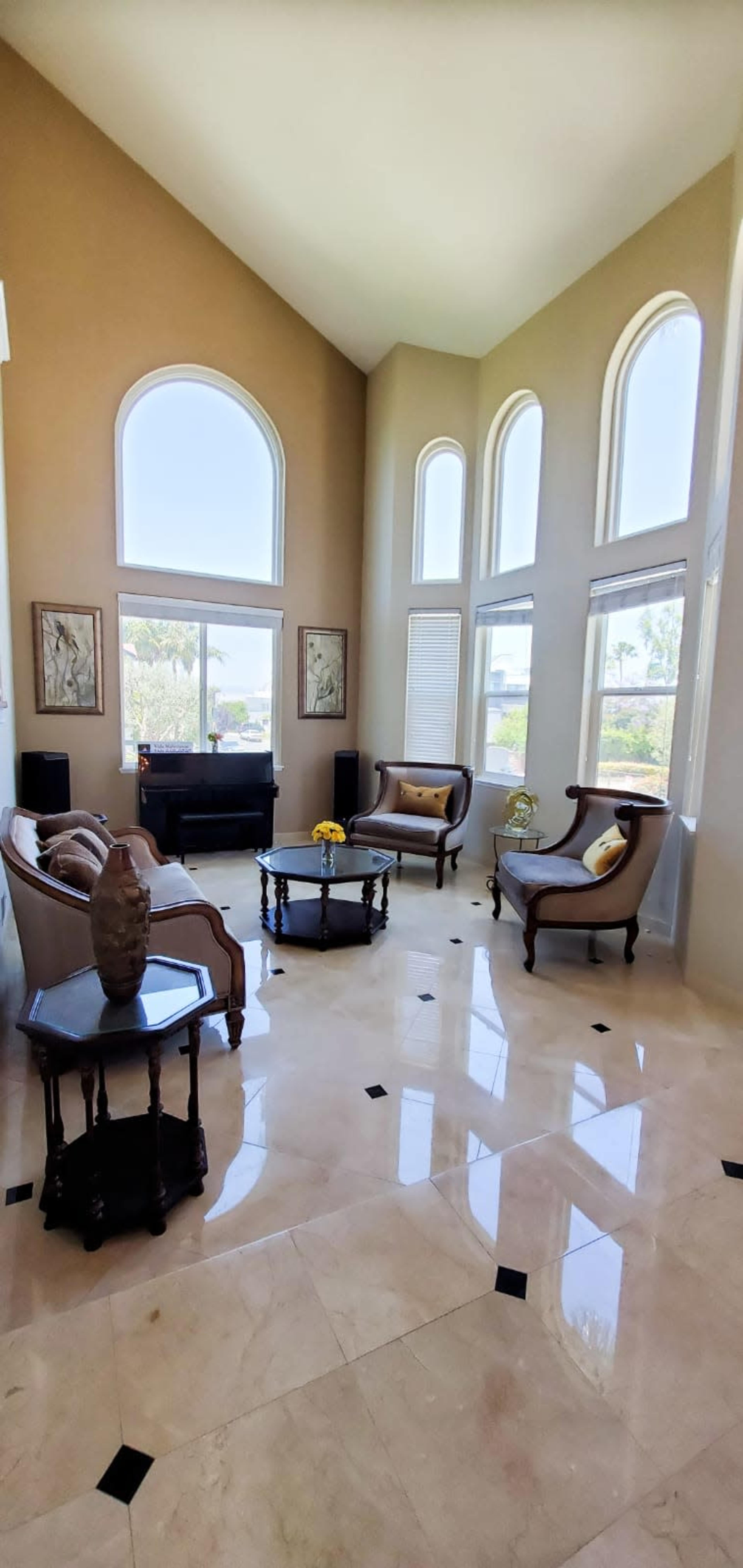 A spacious living room with high ceilings, large windows, and elegant furniture arranged around a central coffee table.