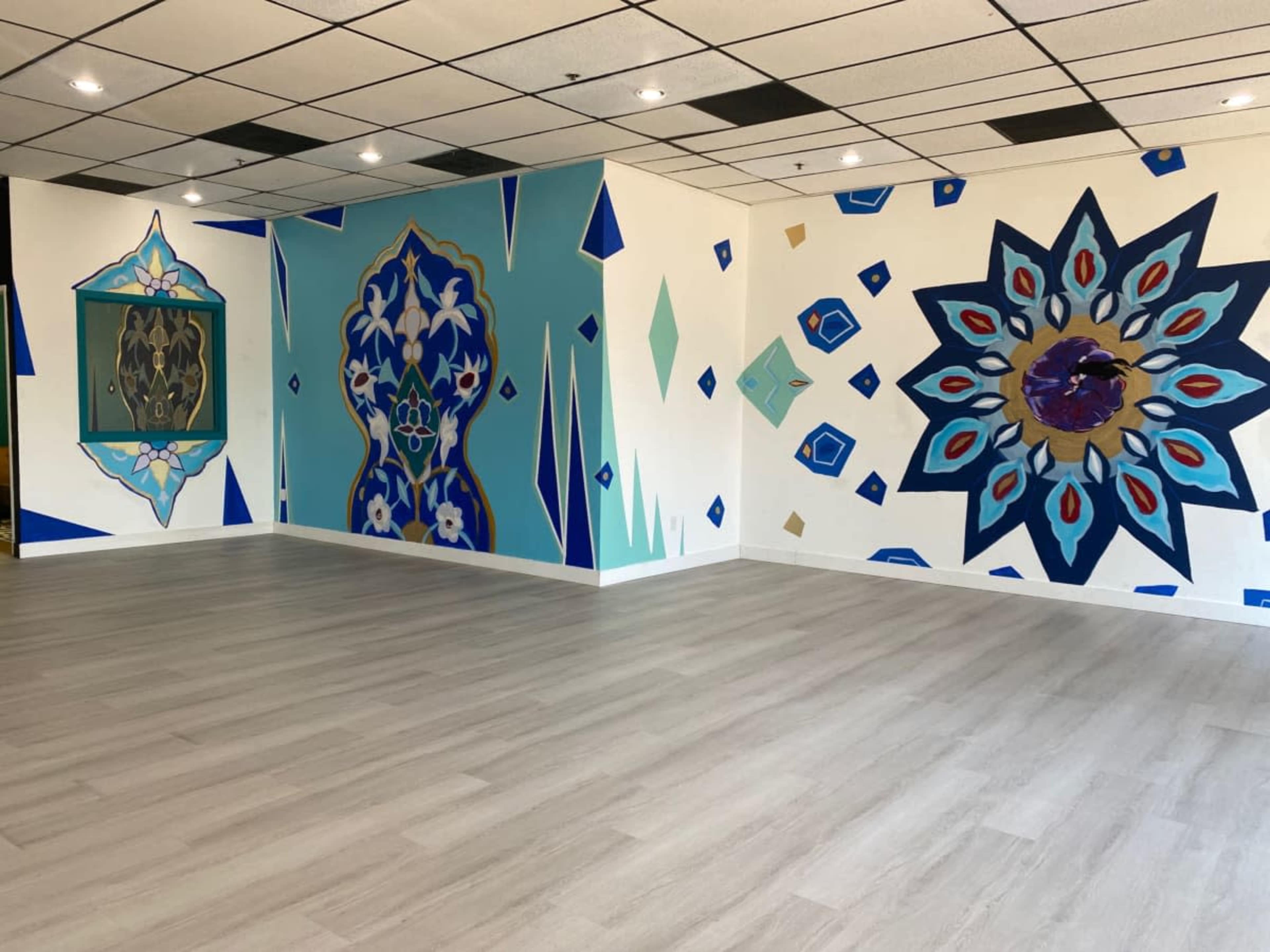 The image shows an interior room with light-colored flooring and walls featuring colorful geometric and floral murals.