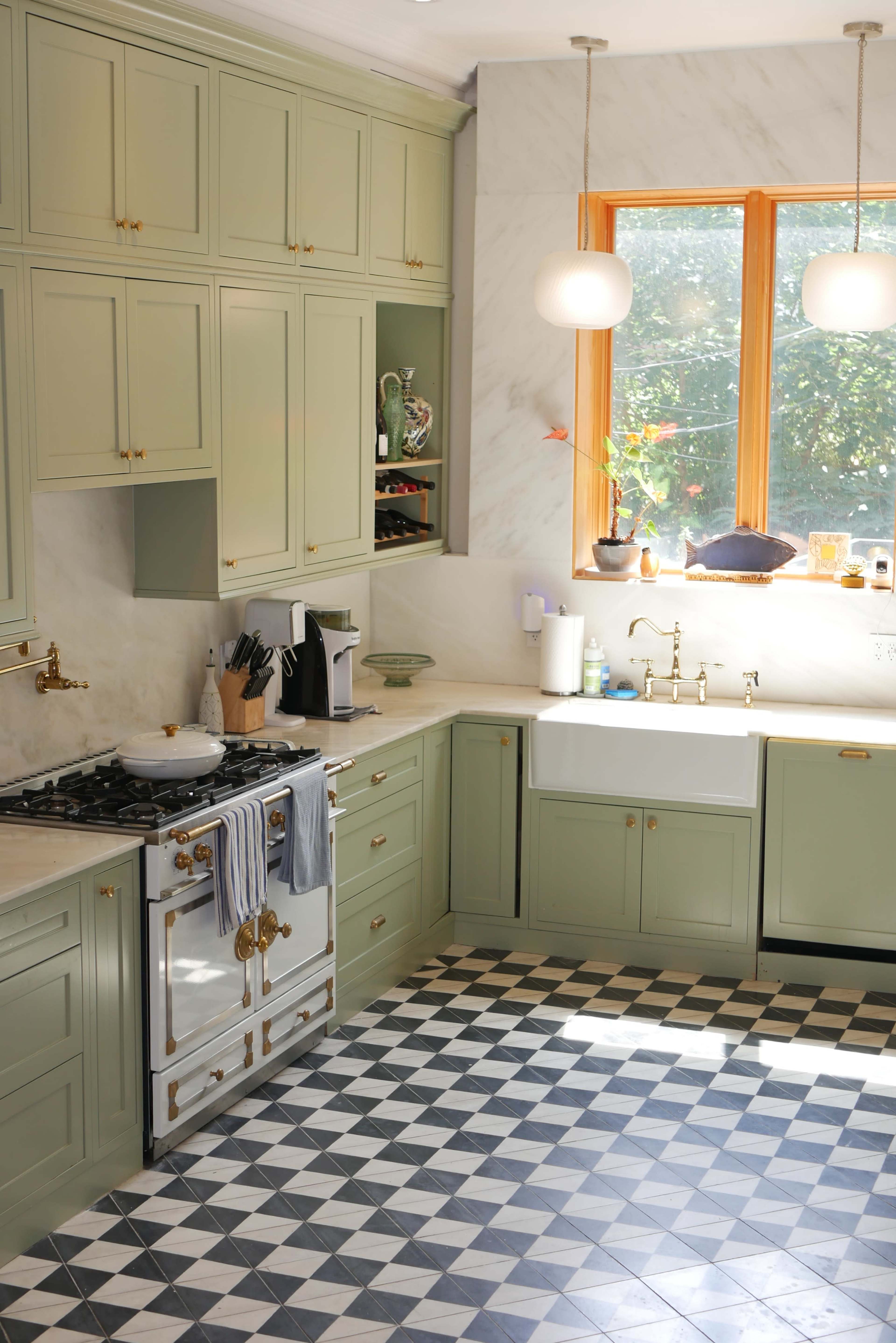 The kitchen features pale green cabinetry, marble countertops, a farmhouse sink, and decorative black and white checkered flooring.