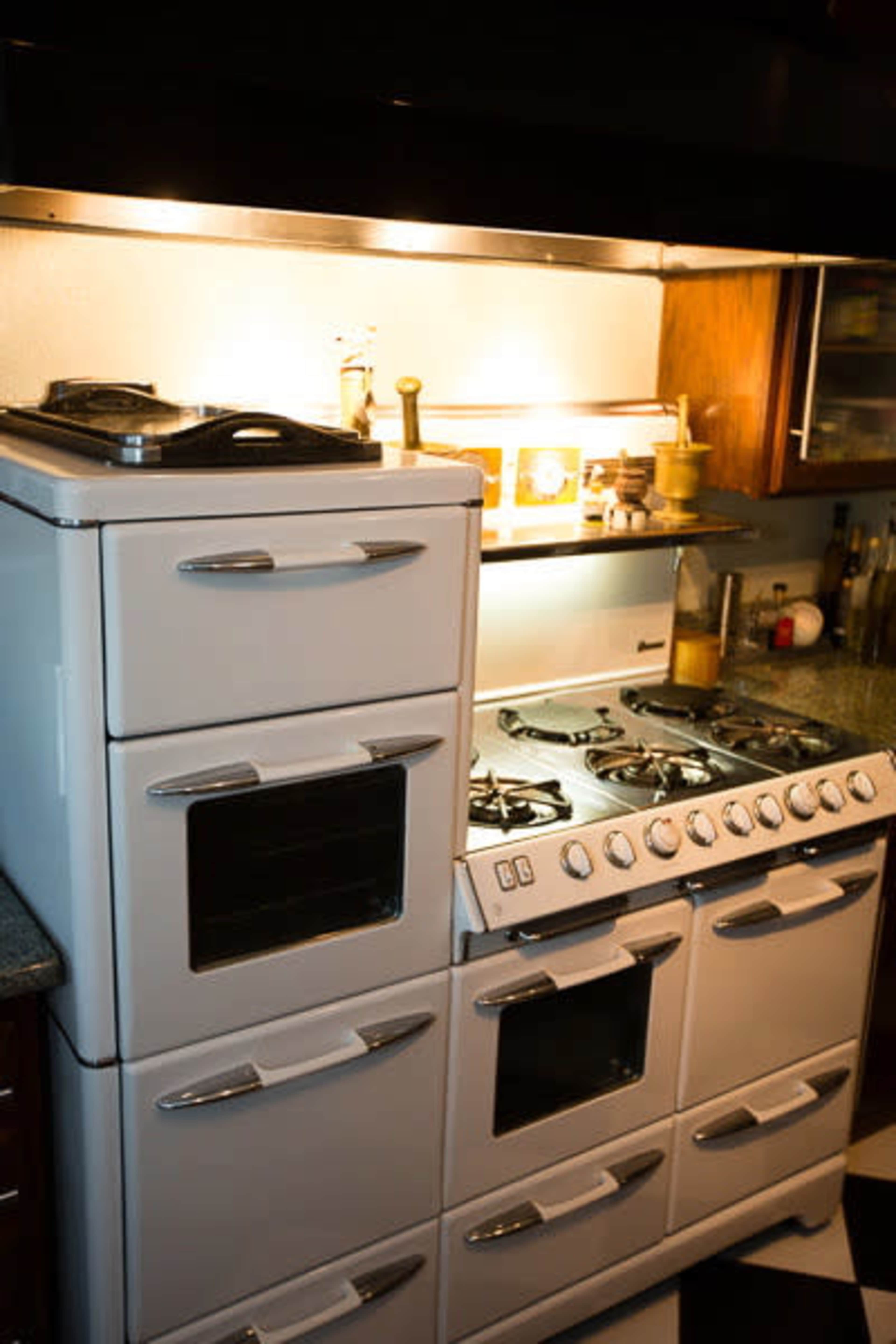 The image shows a retro-style kitchen stove and oven with multiple burners and compartments set against a dark countertop.