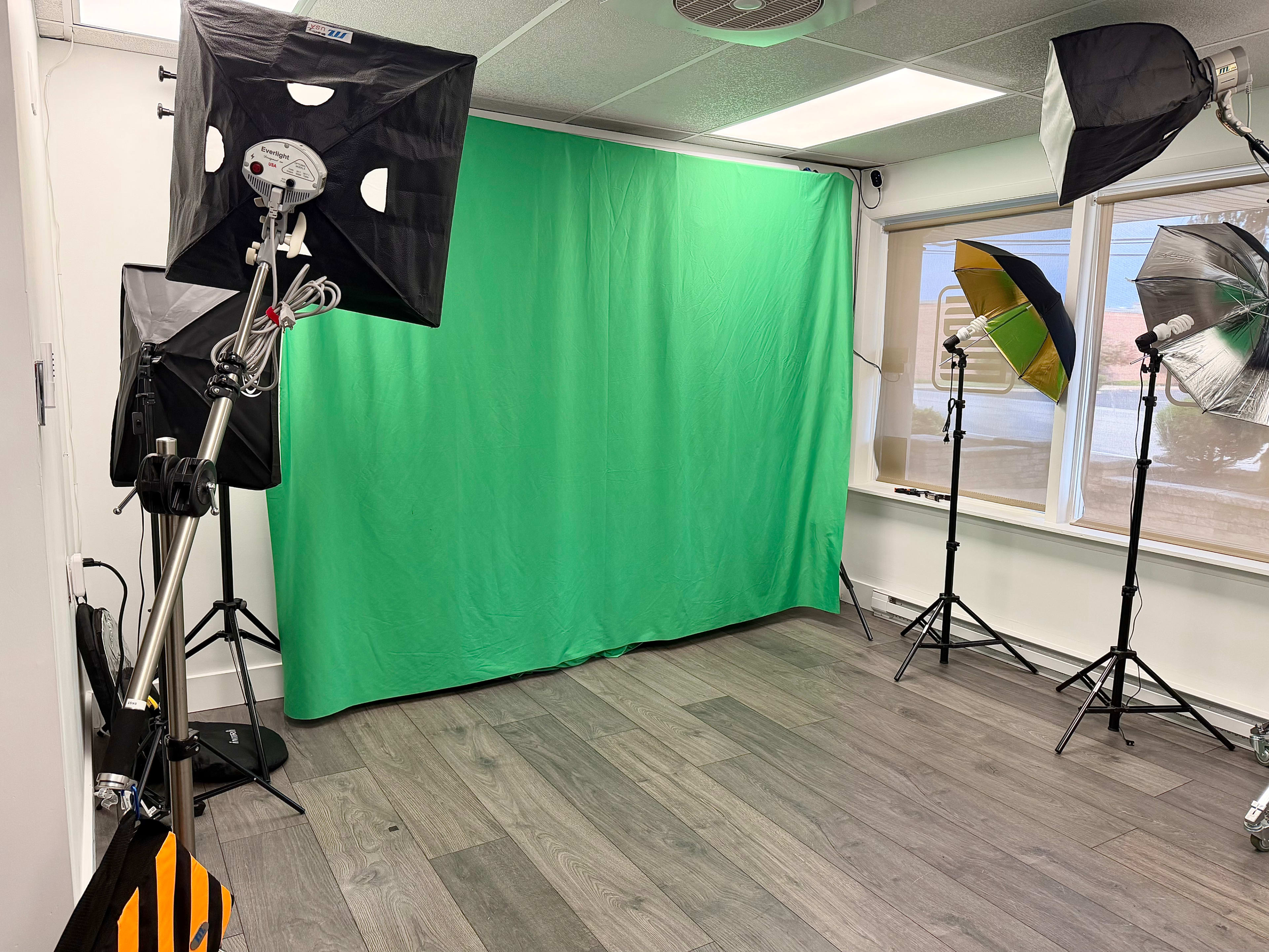 A photography studio is set up with a green screen backdrop and multiple lighting equipment positioned around the space.