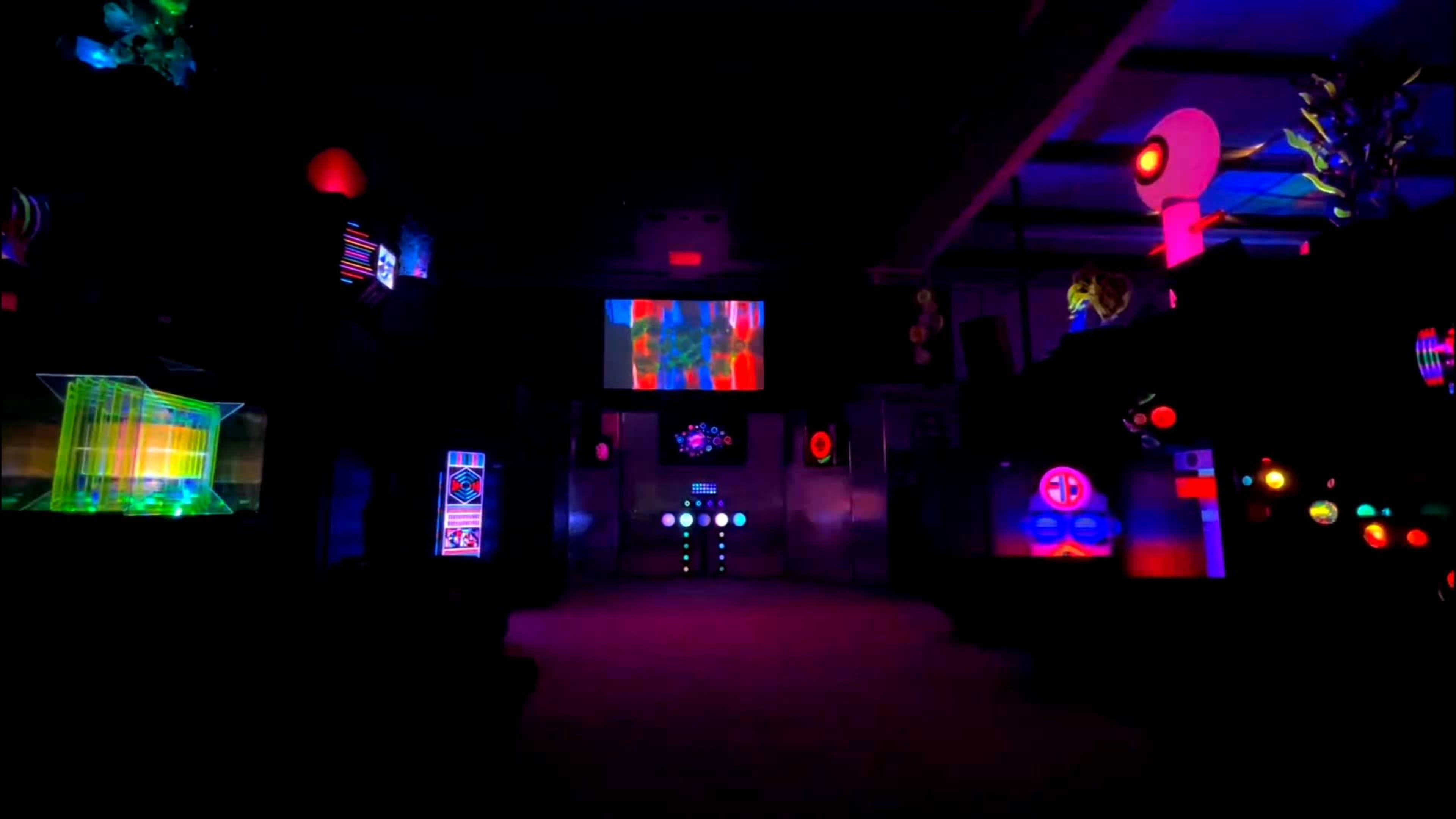 The scene features a dark room illuminated by colorful lights and displays, showcasing various futuristic panels and screens.