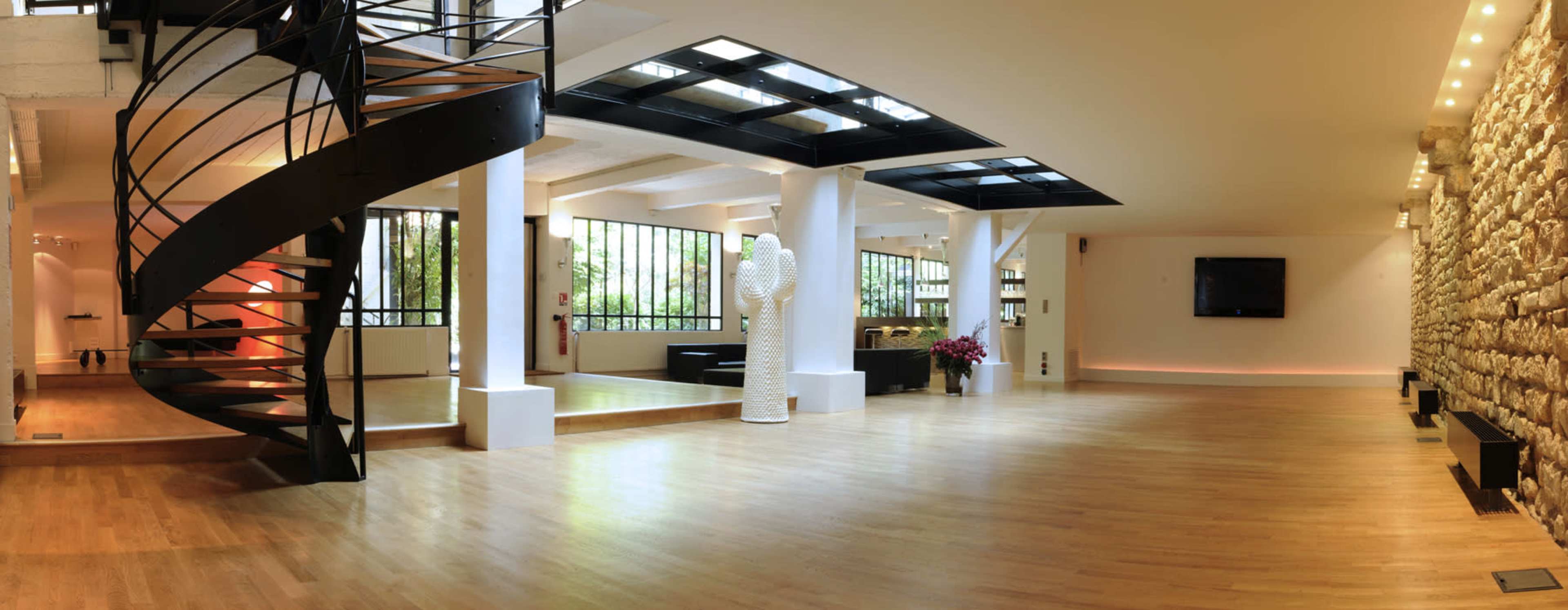 A spacious, modern interior with a spiral staircase, large windows, and a combination of wood and stone flooring.