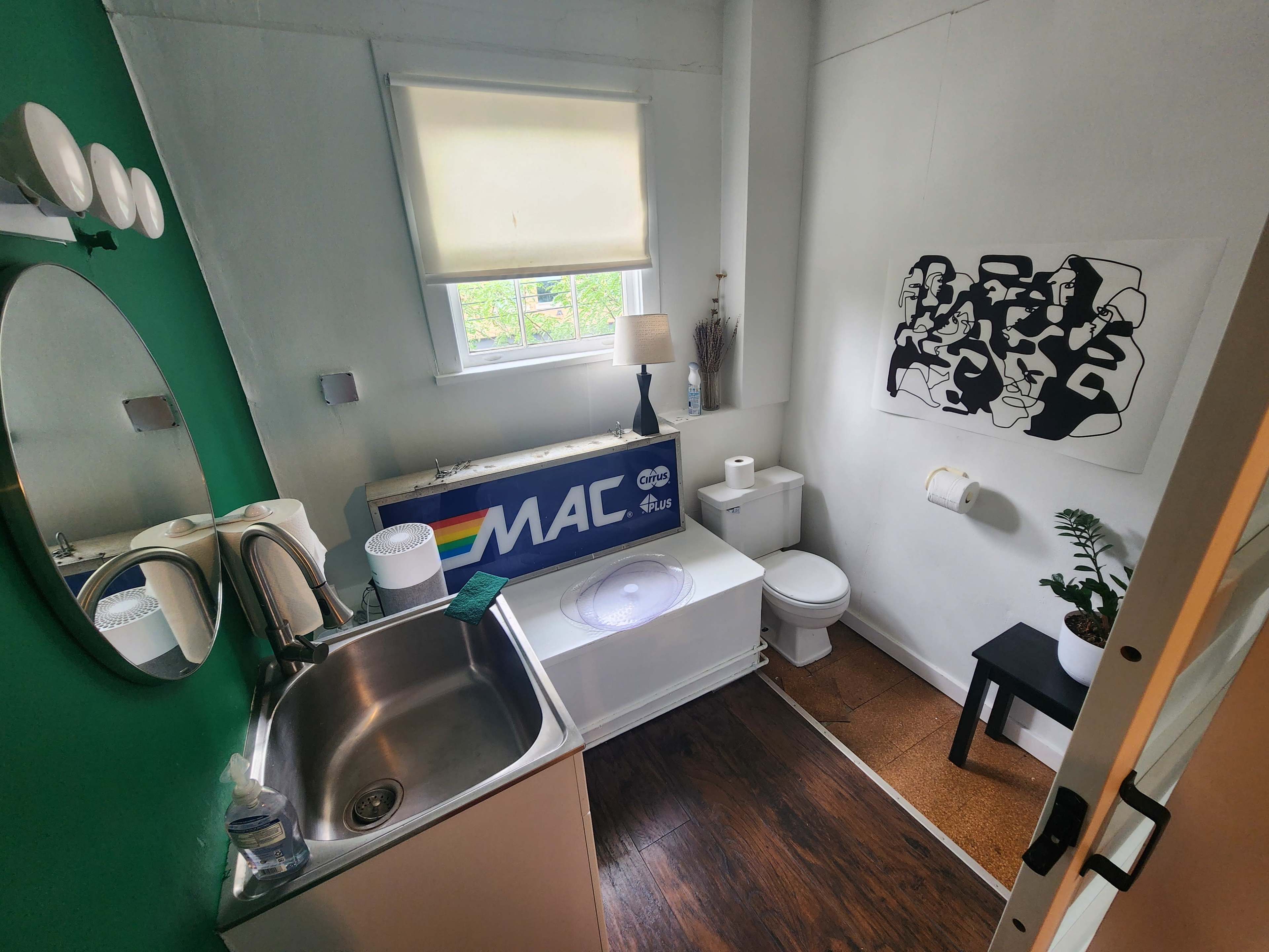 A small bathroom featuring a sink, toilet, bathtub, and a wall with a black-and-white artwork.