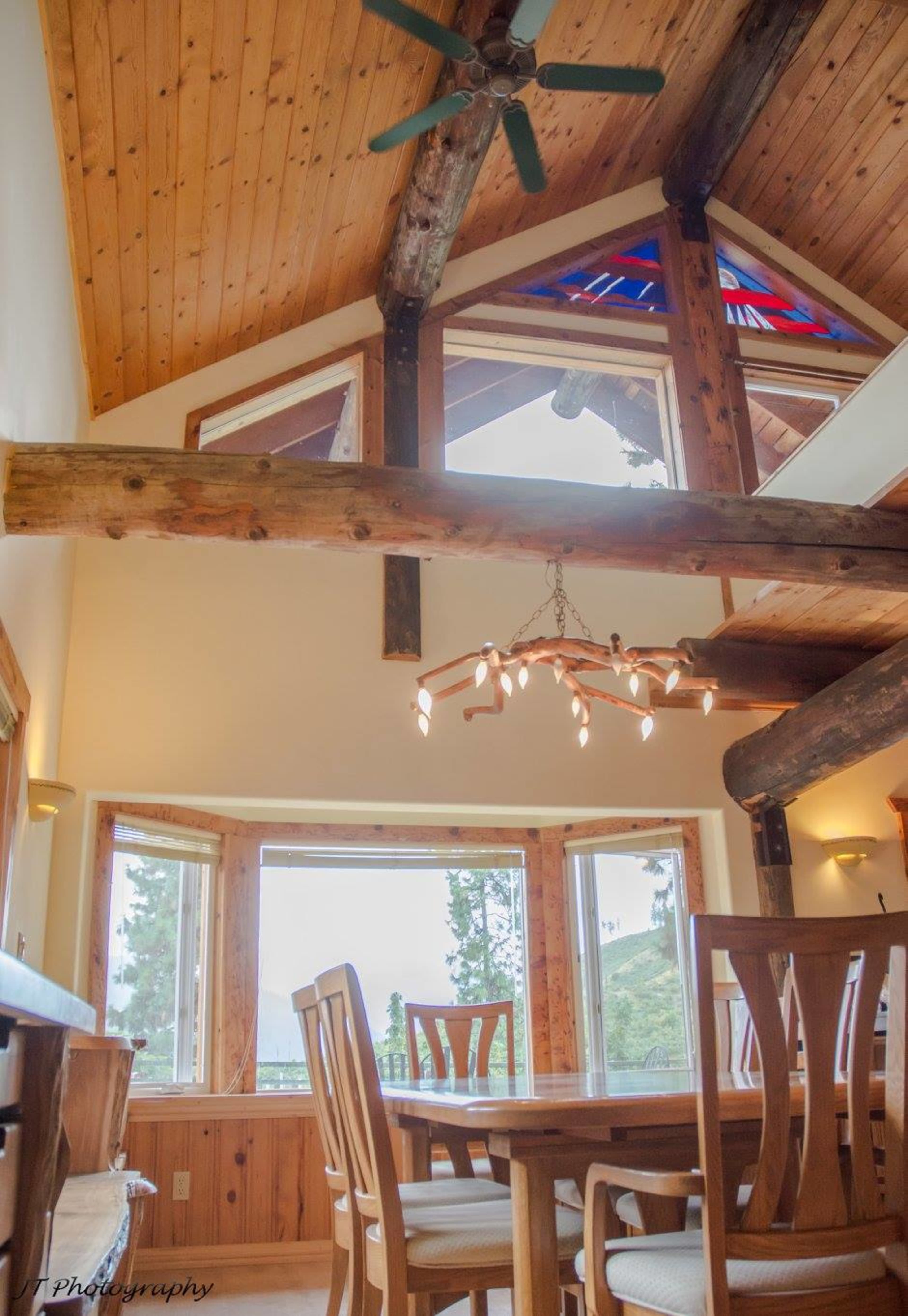A well-lit dining area with wooden beams and large windows that open to a scenic view.