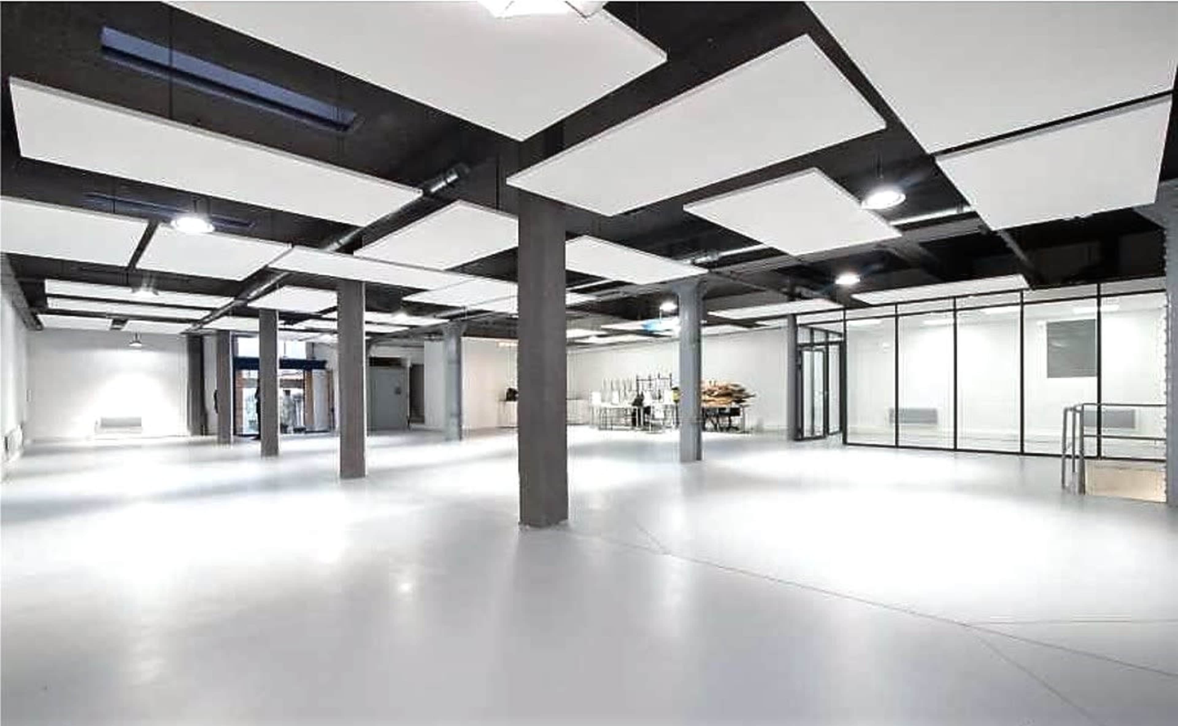 A spacious, empty interior with white walls, a smooth floor, and several overhead light fixtures.