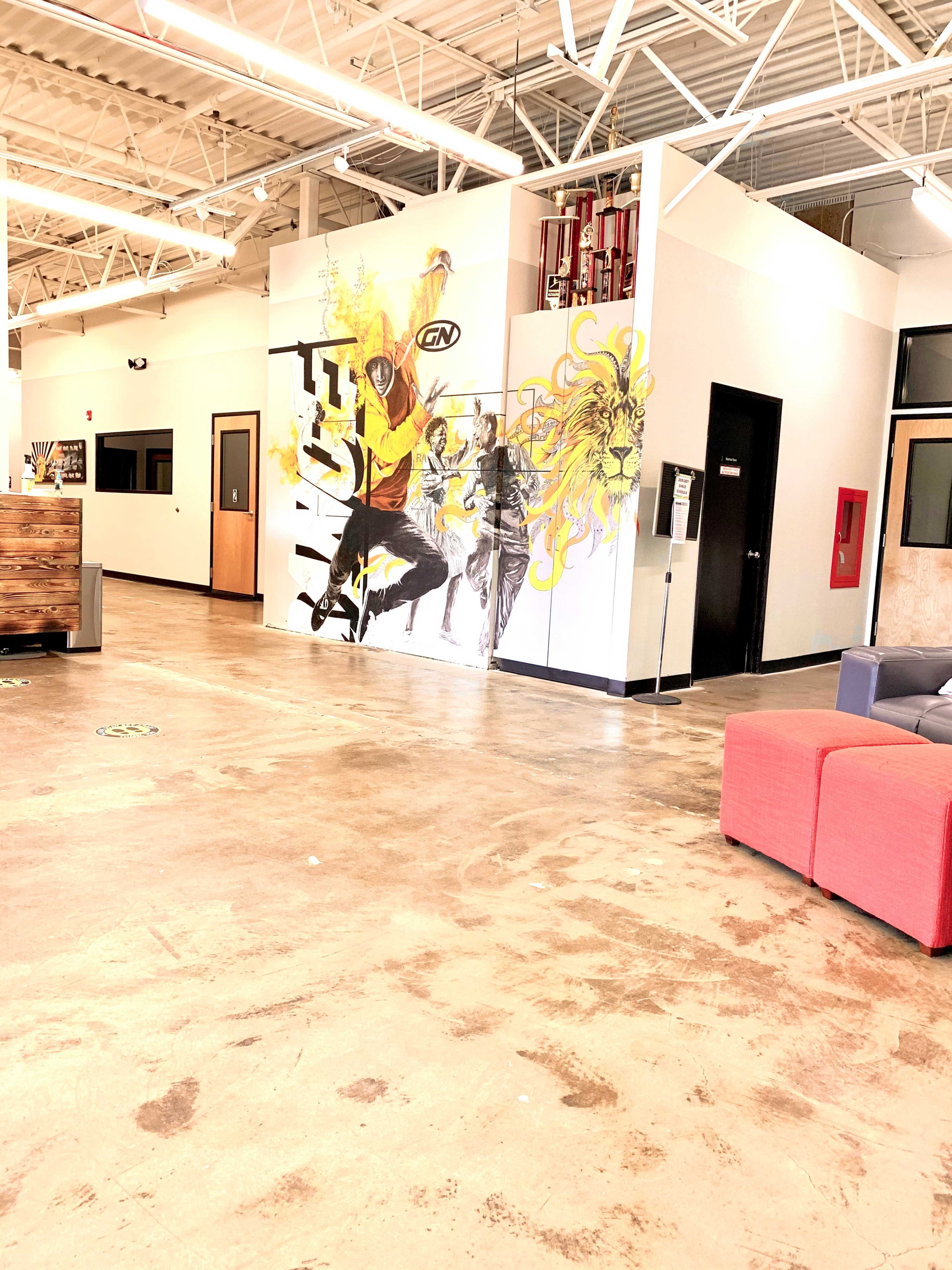 A spacious interior with a colorful mural on one wall and a cozy seating area featuring red and gray furniture.