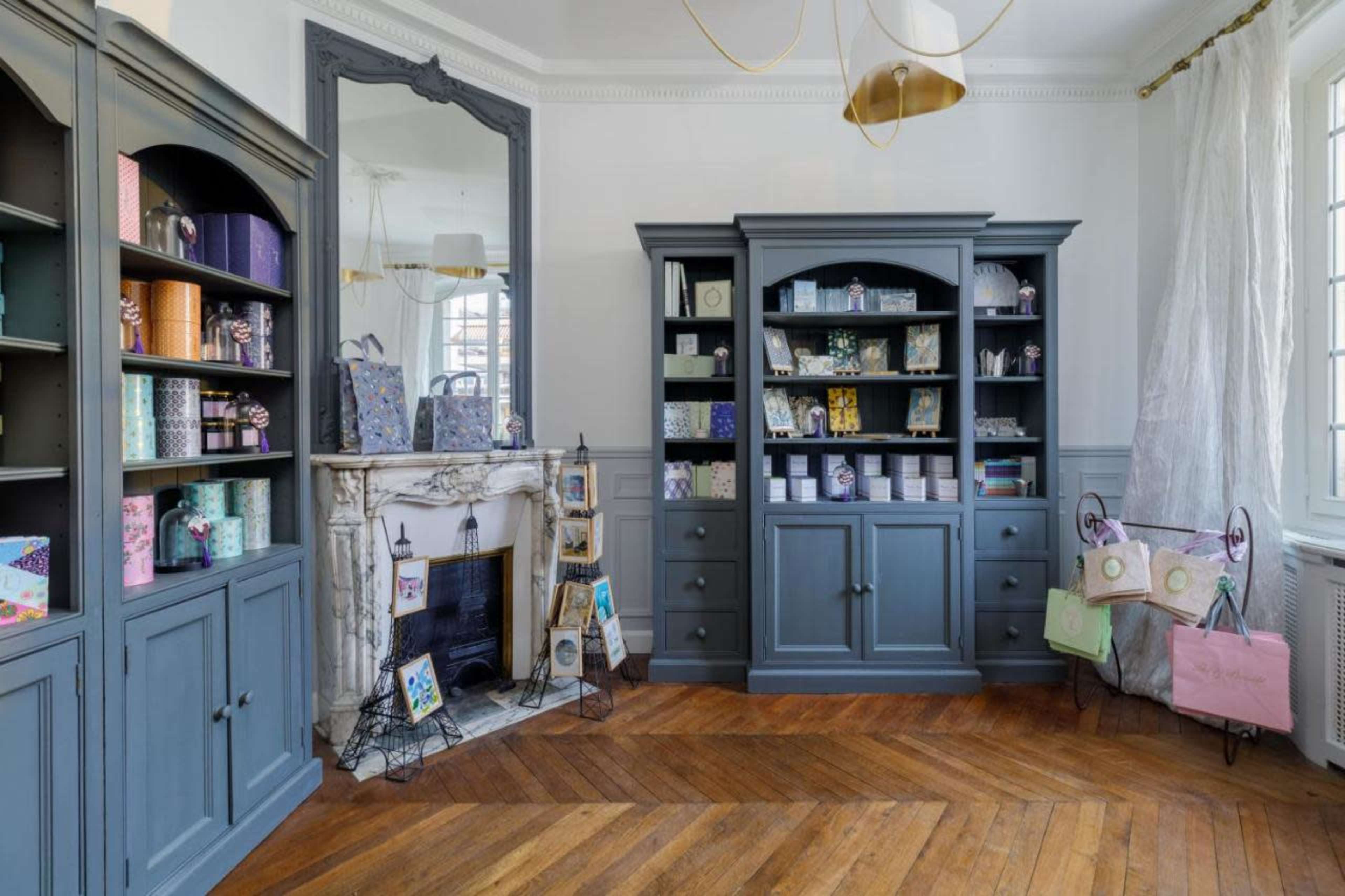A well-furnished room featuring a fireplace, two large bookshelves filled with colorful boxes and decorative items, and a mirror reflecting light.