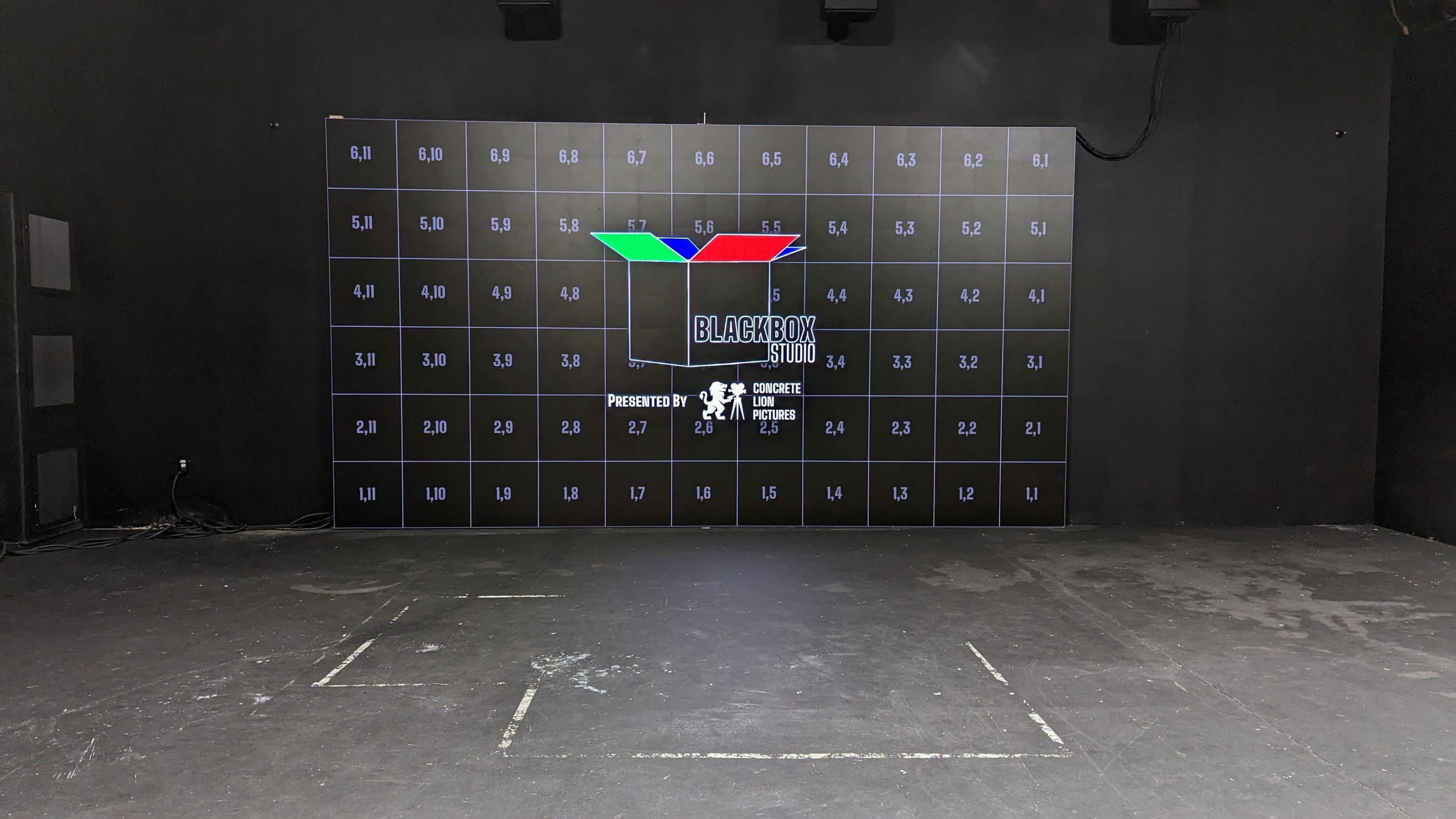 A large black wall display with a grid of numbered squares and a central logo that reads "BLACKBOX 510," set in a dark, empty room.