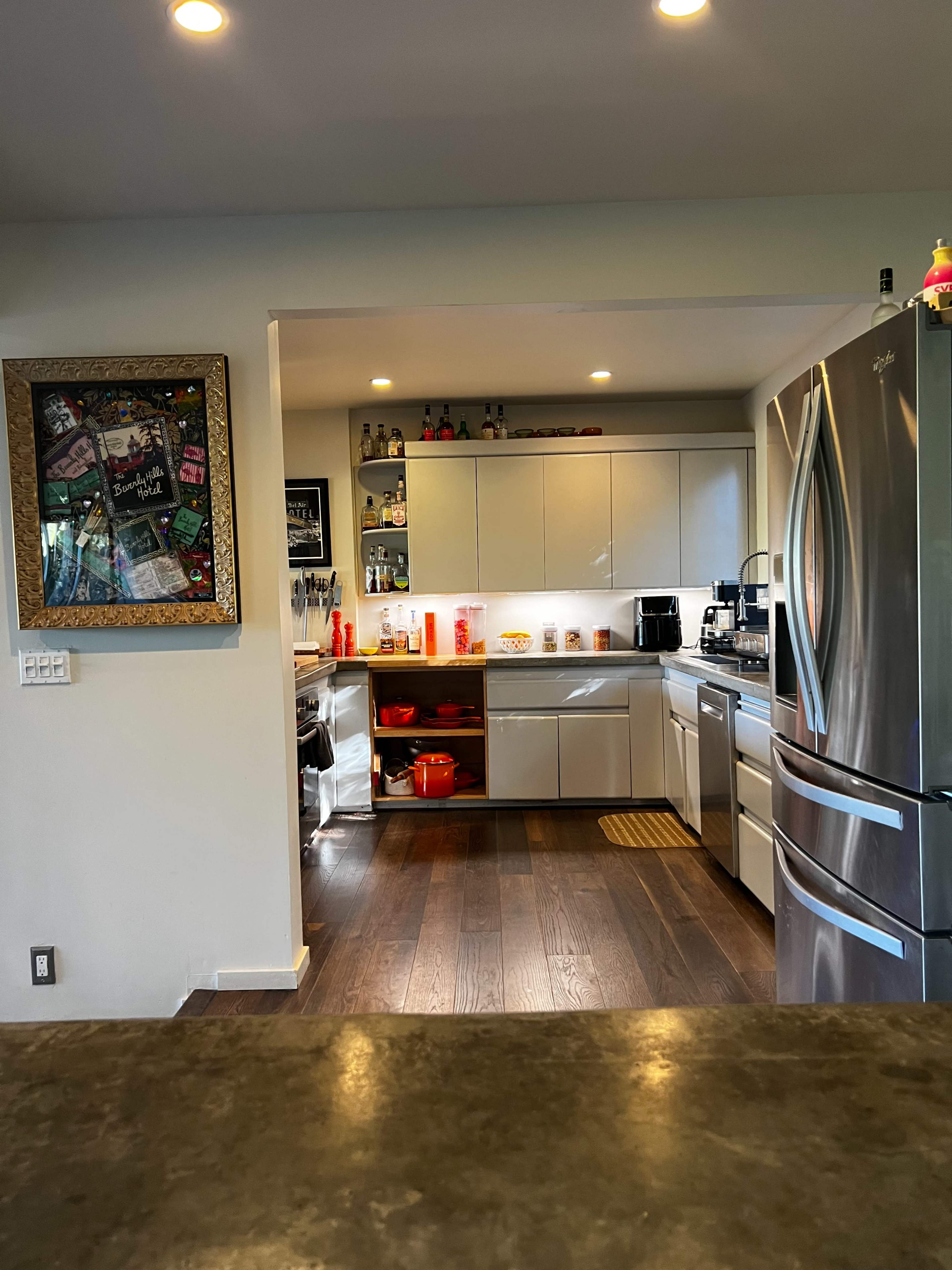 A modern kitchen features stainless steel appliances, light-colored cabinets, and a hardwood floor.