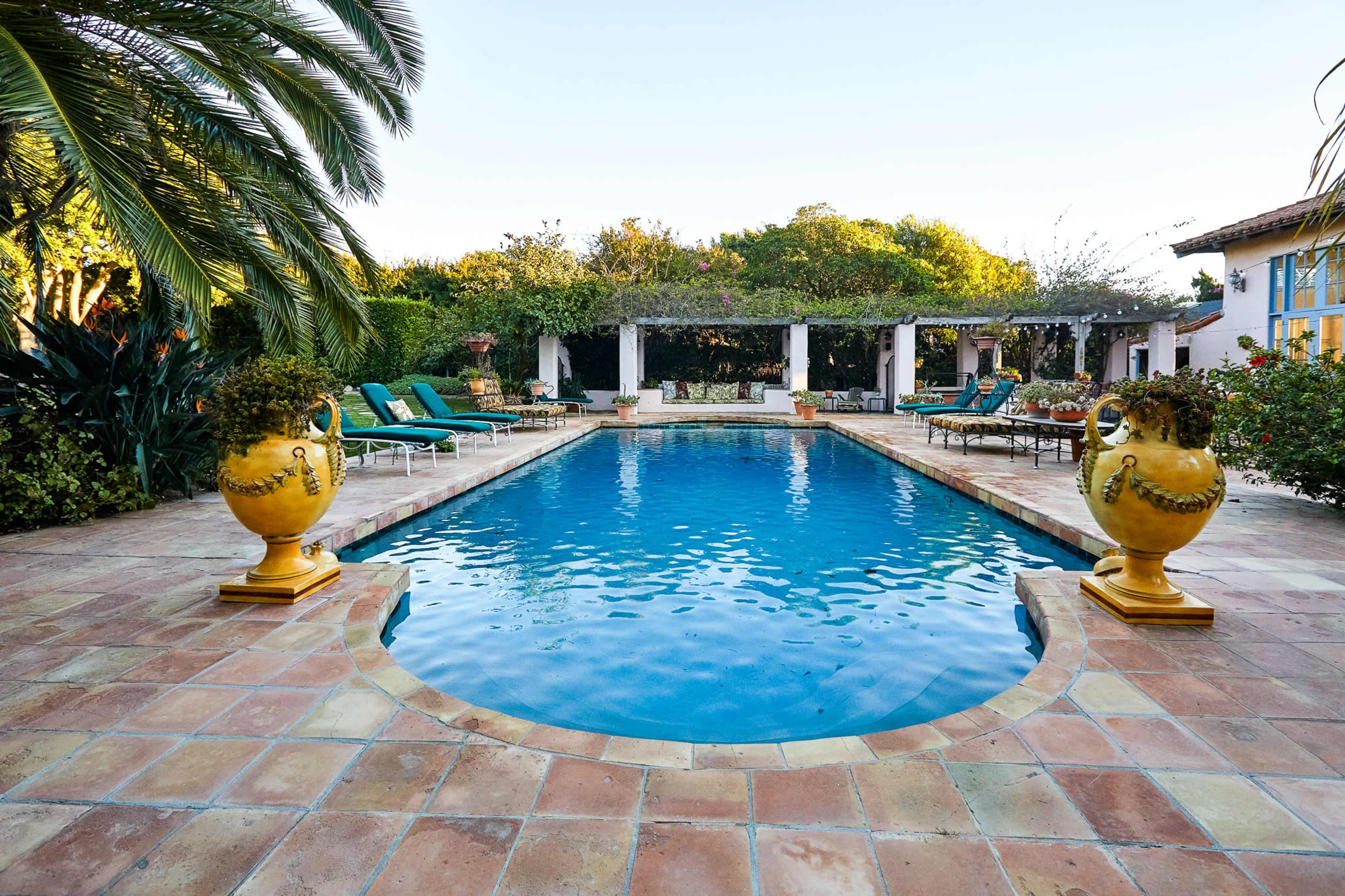 A swimming pool surrounded by lounge chairs and decorative planters in a landscaped outdoor area.