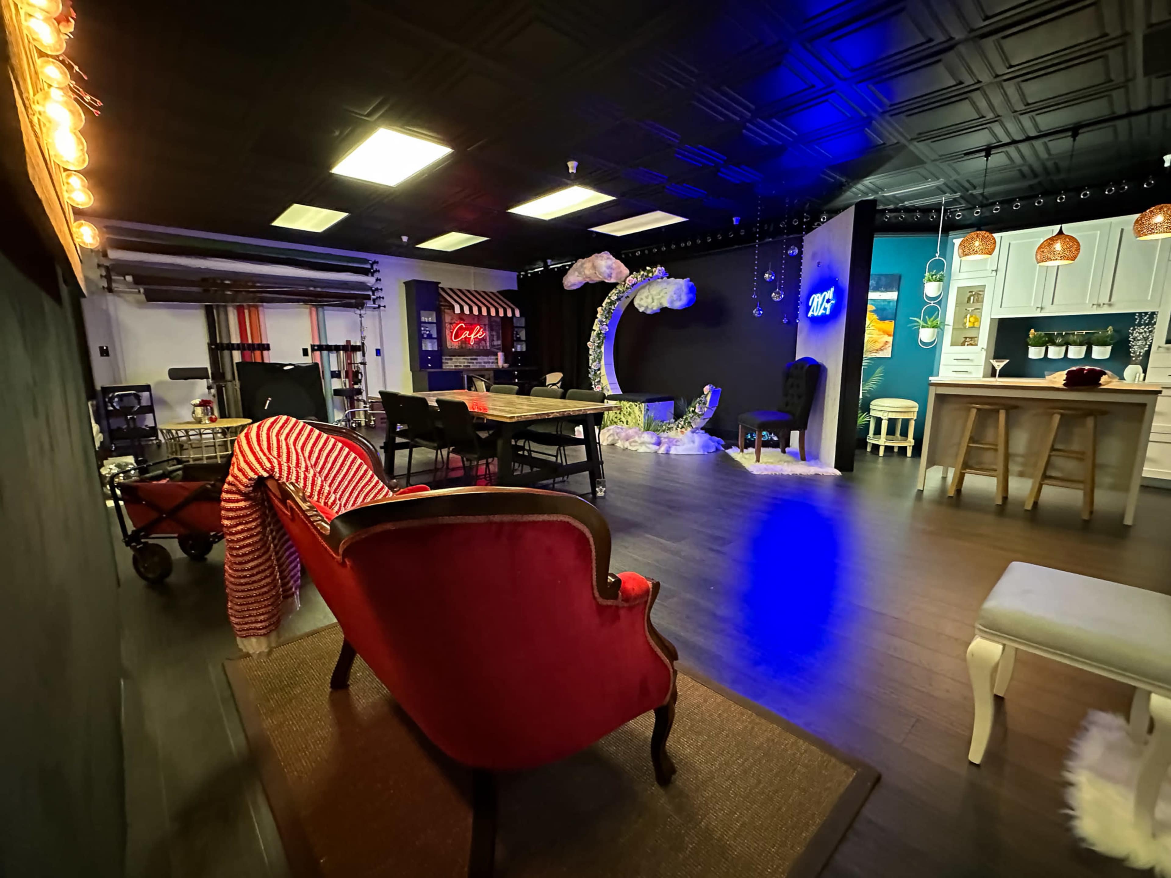 The image shows a spacious creative studio with a mix of seating areas, decorative elements, and various light fixtures.