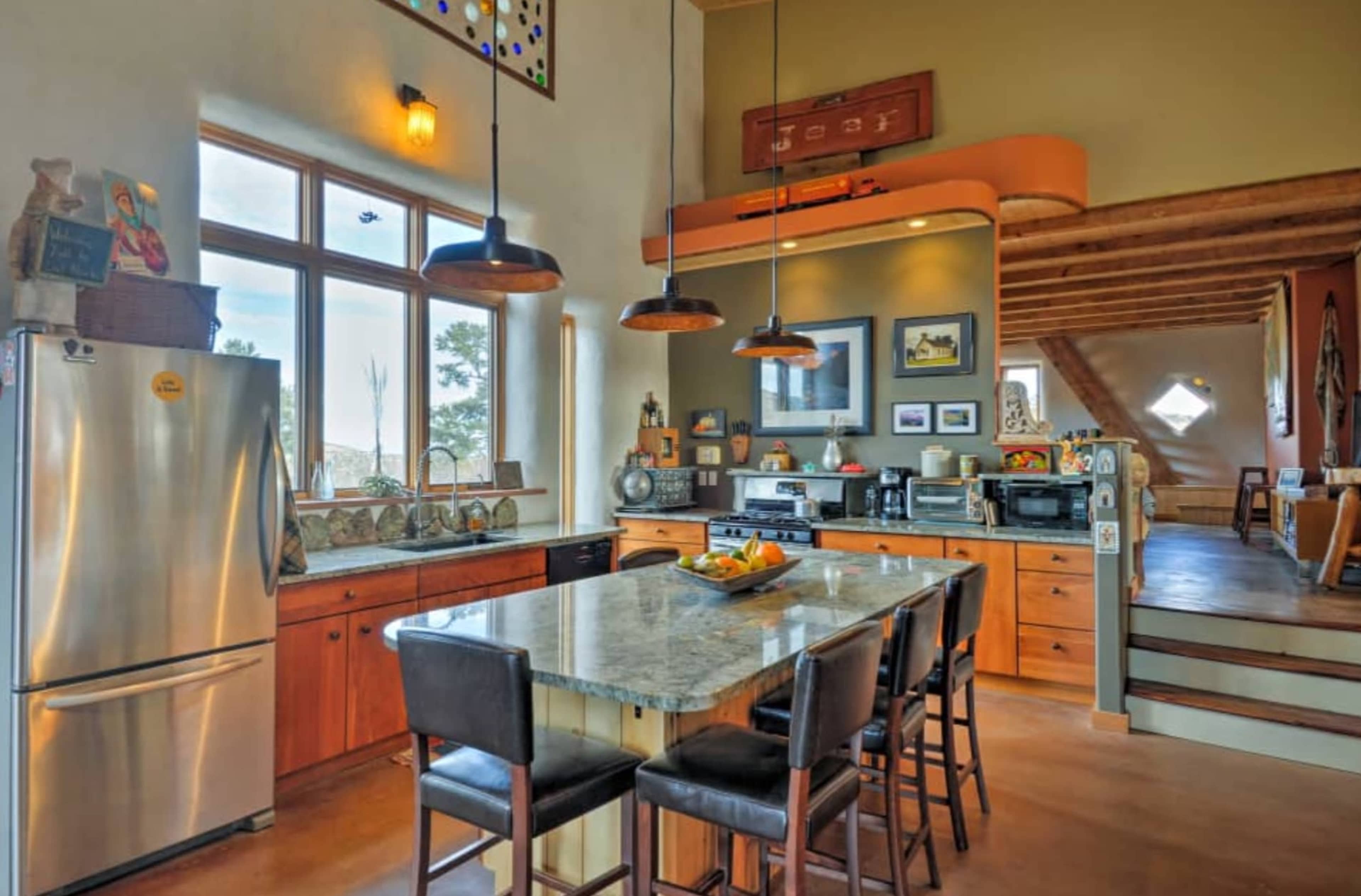 A modern kitchen featuring a central island with seating, stainless steel appliances, and large windows that provide ample natural light.