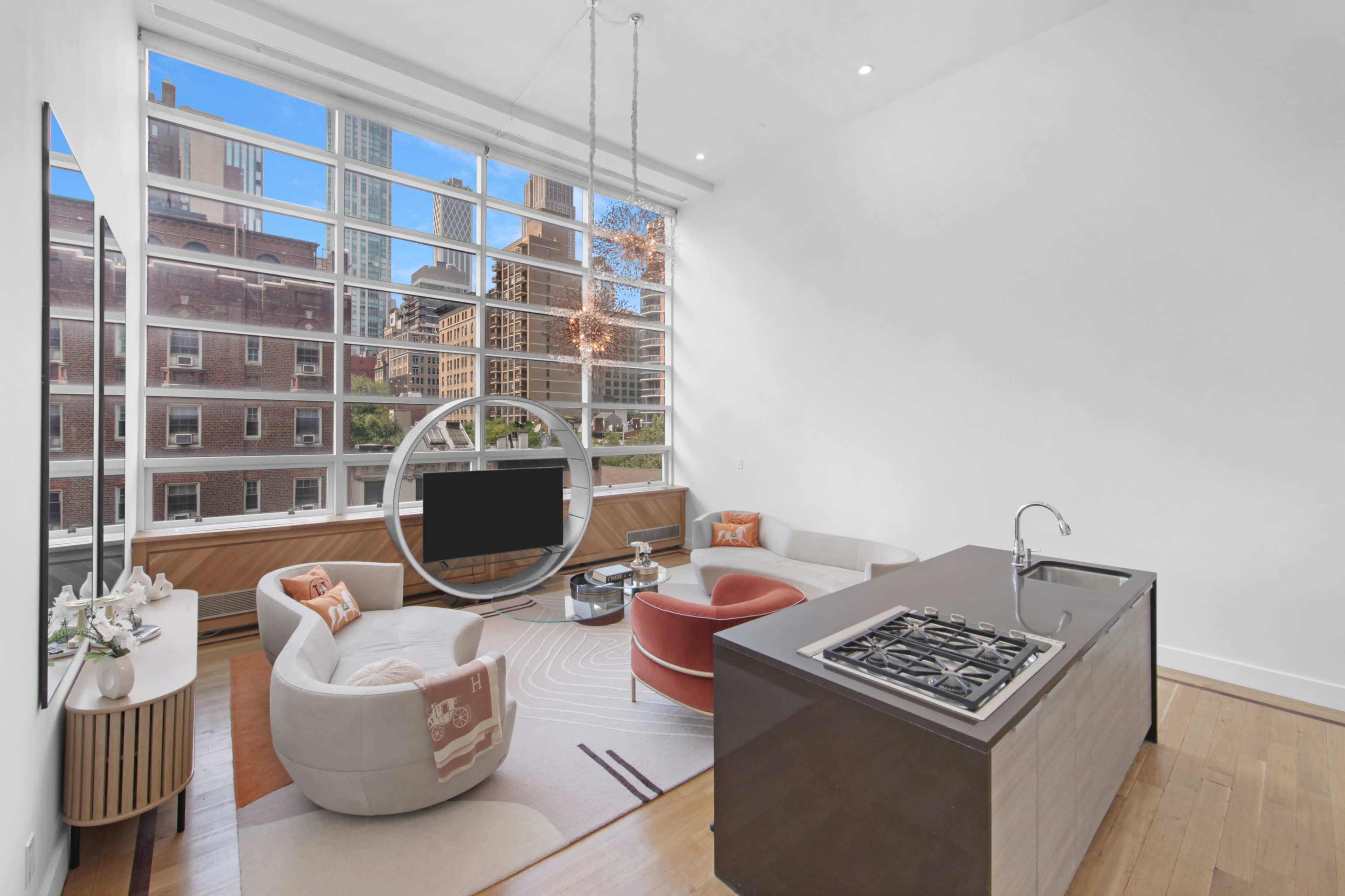 The image shows a modern living room with large windows, a circular television stand, and an open kitchen area featuring a gas cooktop.