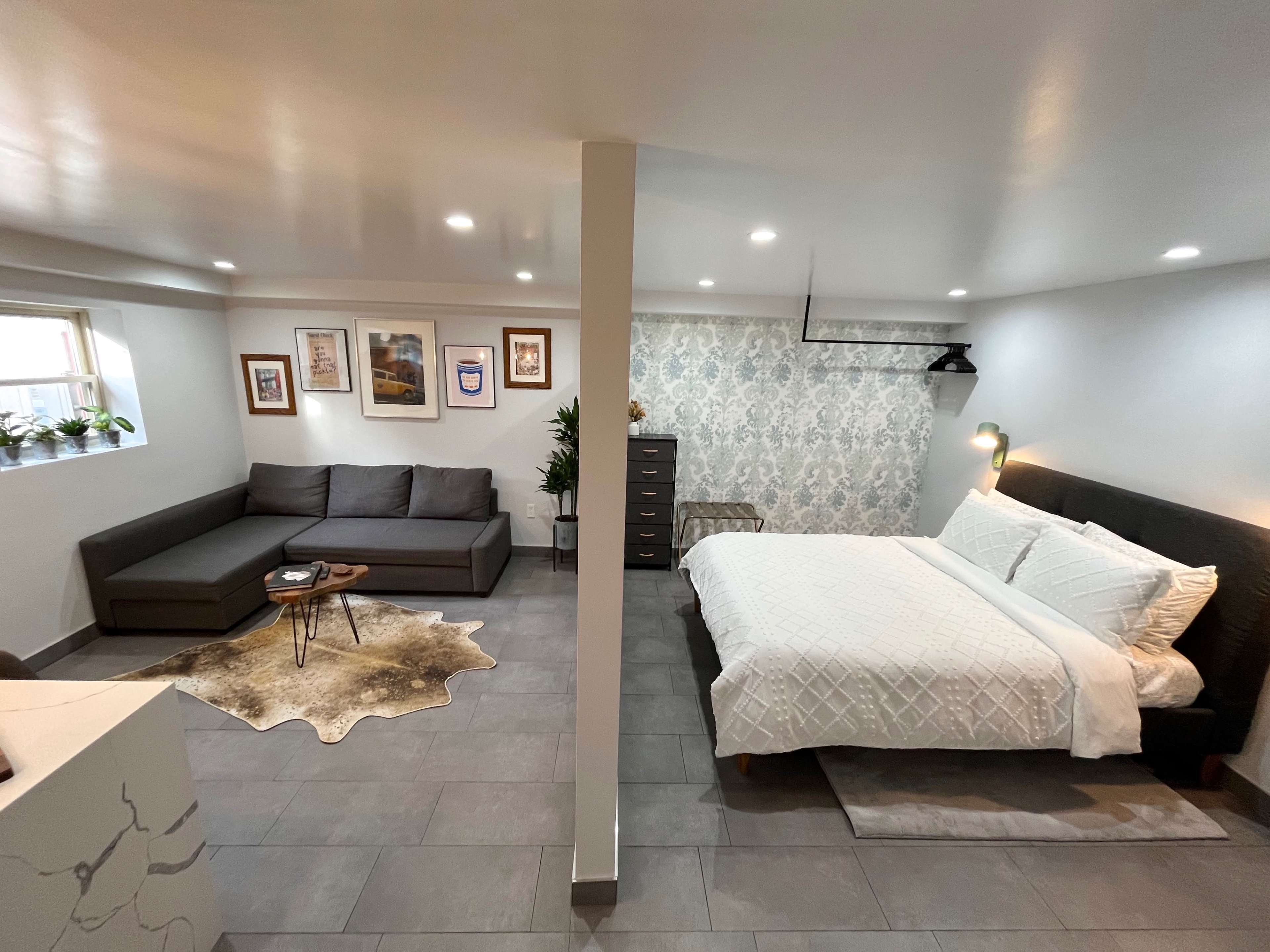 A modern studio apartment featuring a sleeping area with a bed and a sitting area with a sofa and coffee table.