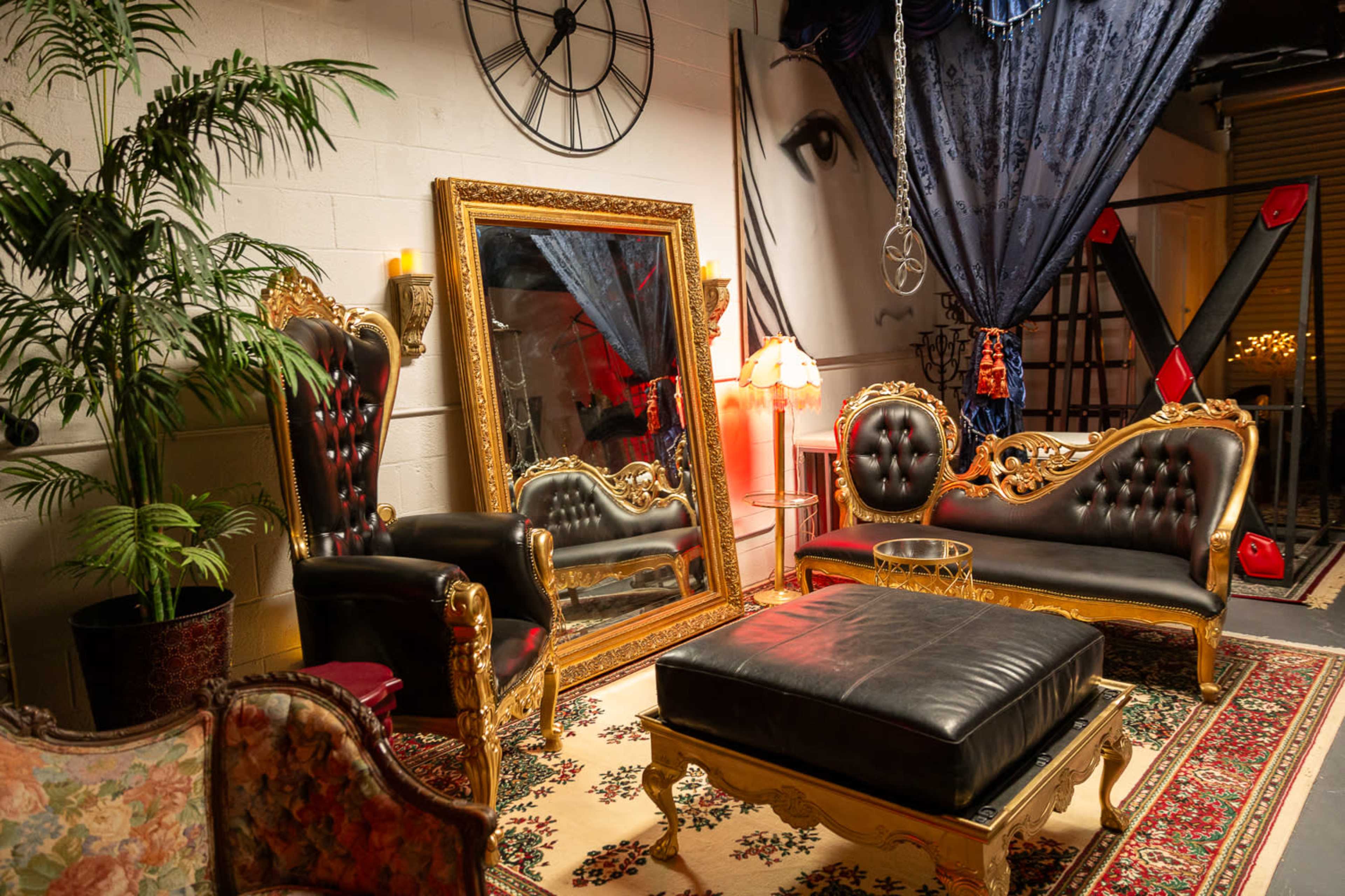 The image depicts a stylized lounge area featuring ornate furniture, a large mirror, and decorative elements, including a potted plant and a clock on the wall.