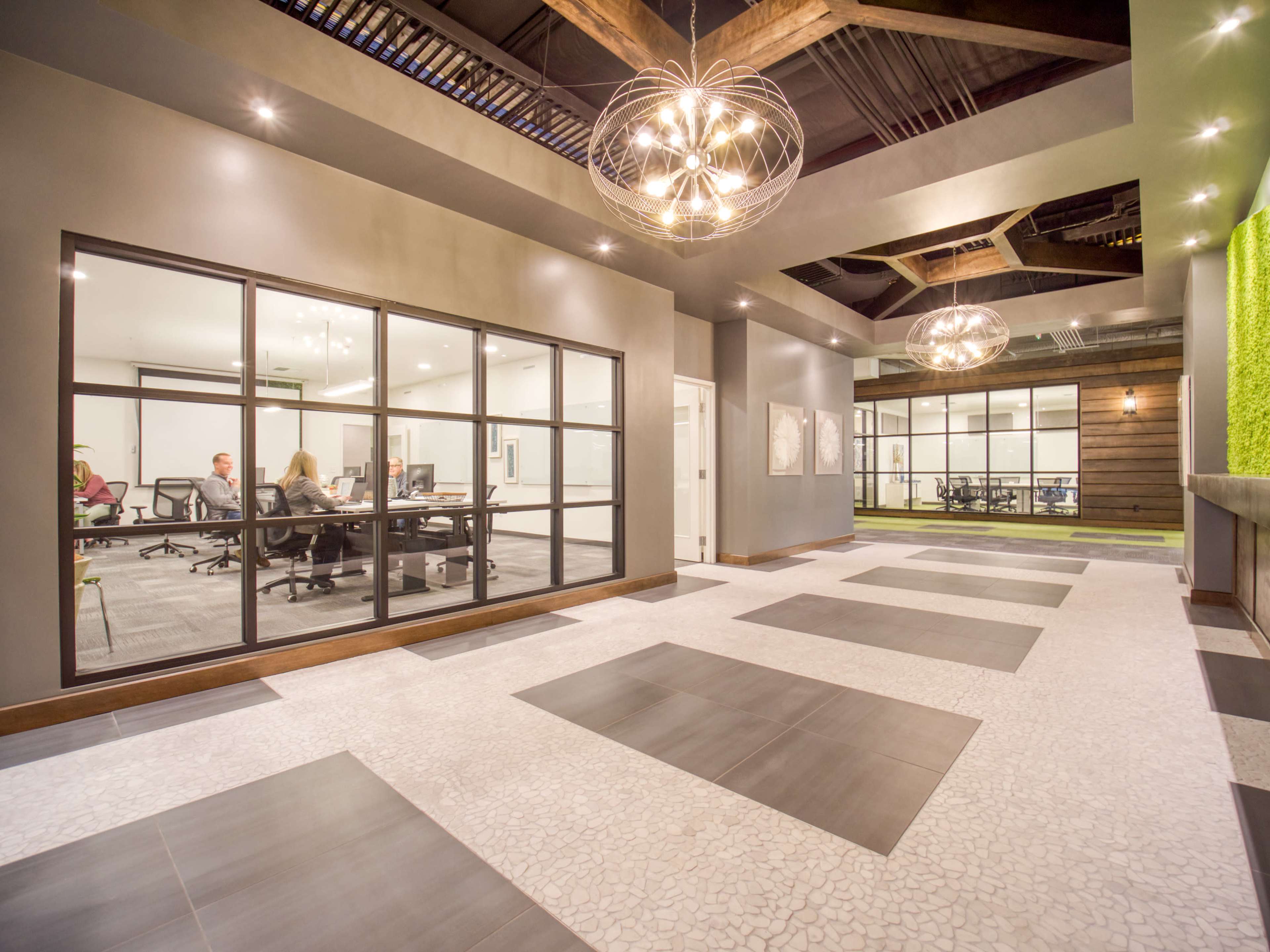 A modern office space featuring a large, open area with a glass-walled meeting room and decorative lighting overhead.