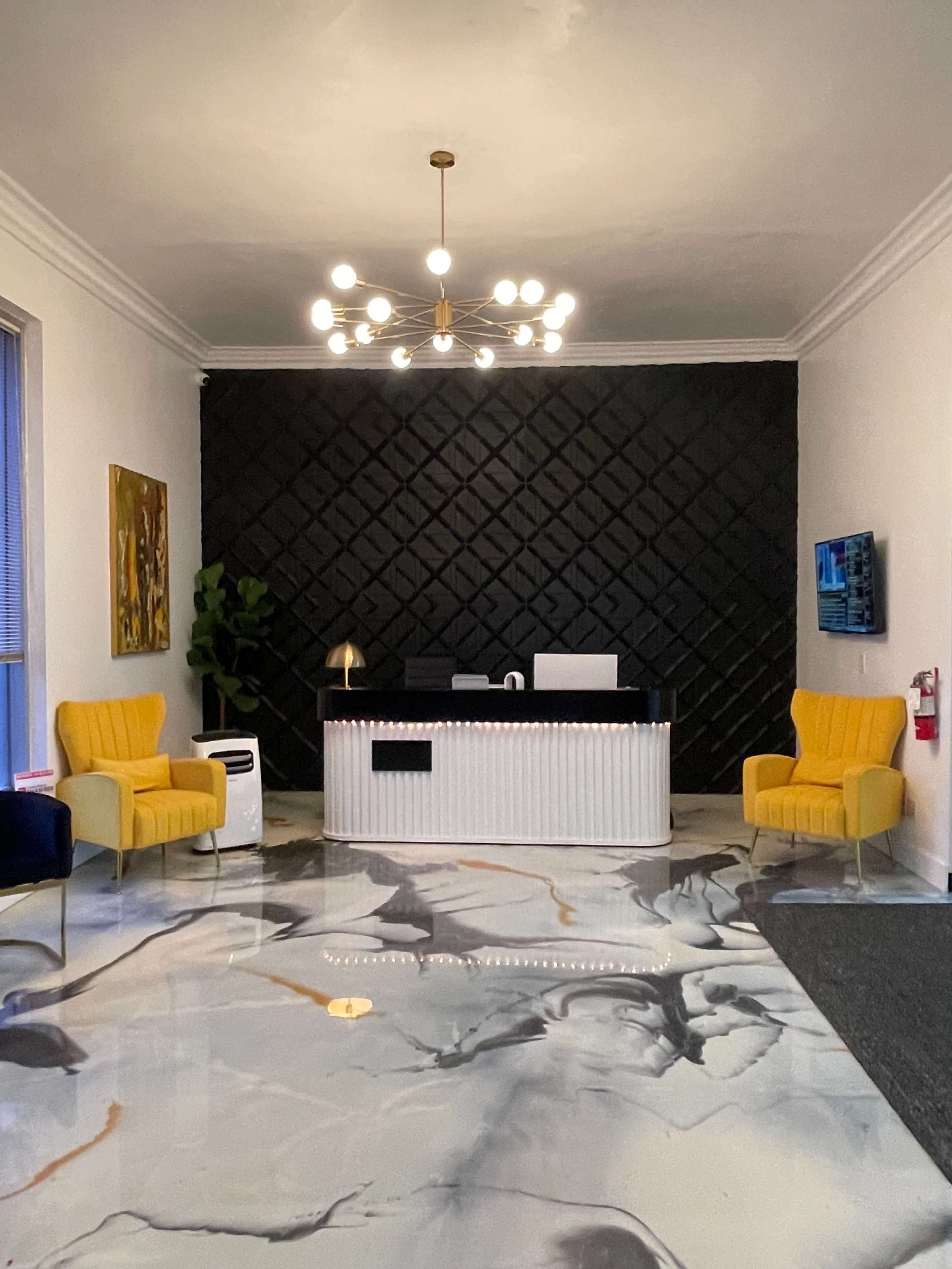 The image shows a modern reception area featuring a black and white color scheme, with a striped front desk, yellow armchairs, and a marbled floor.