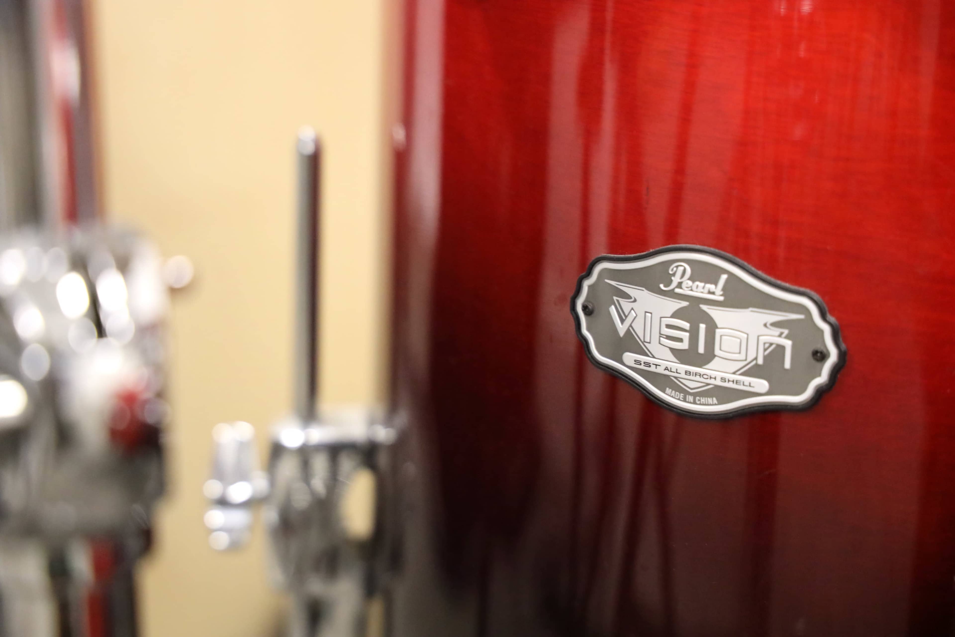 The image shows the logo of a Pearl Vision drum set mounted on a red drum.