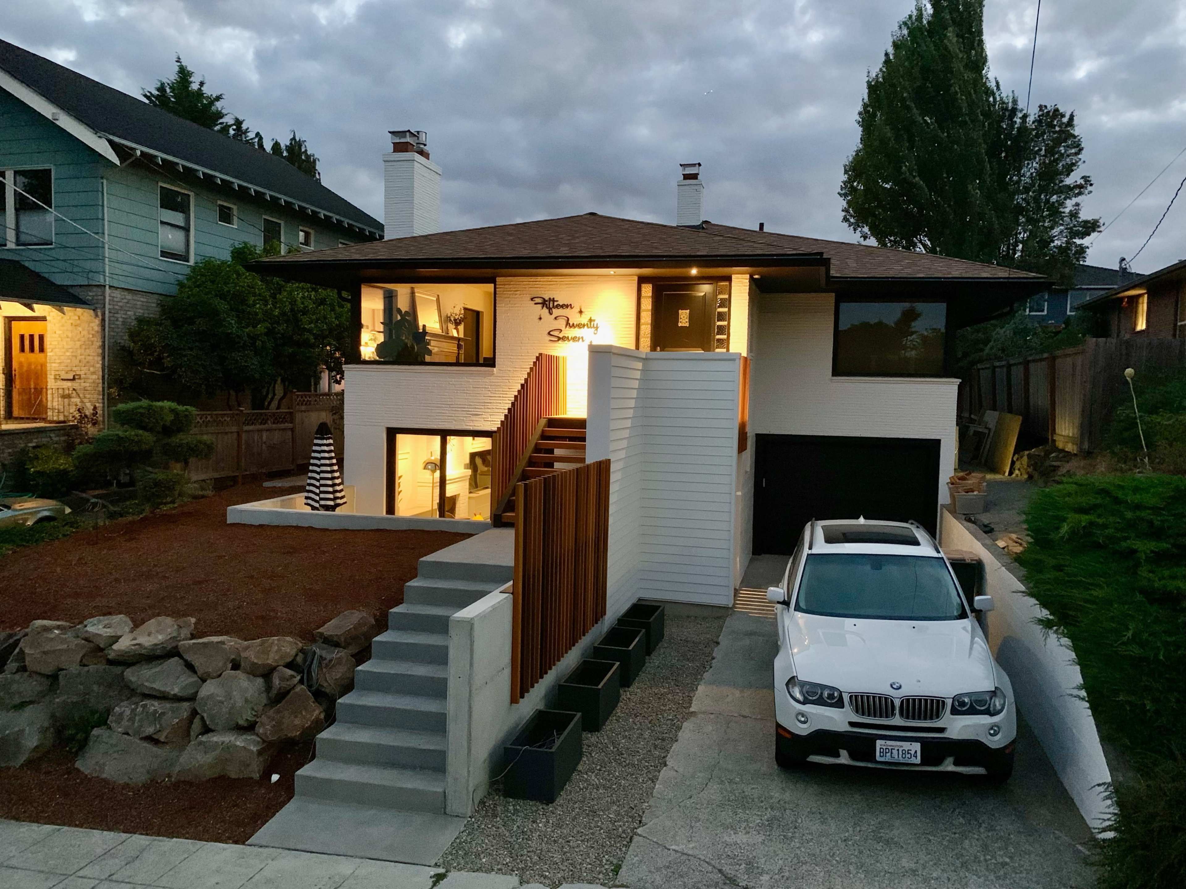 A modern two-story house with a landscaped yard and a white SUV parked in the driveway.