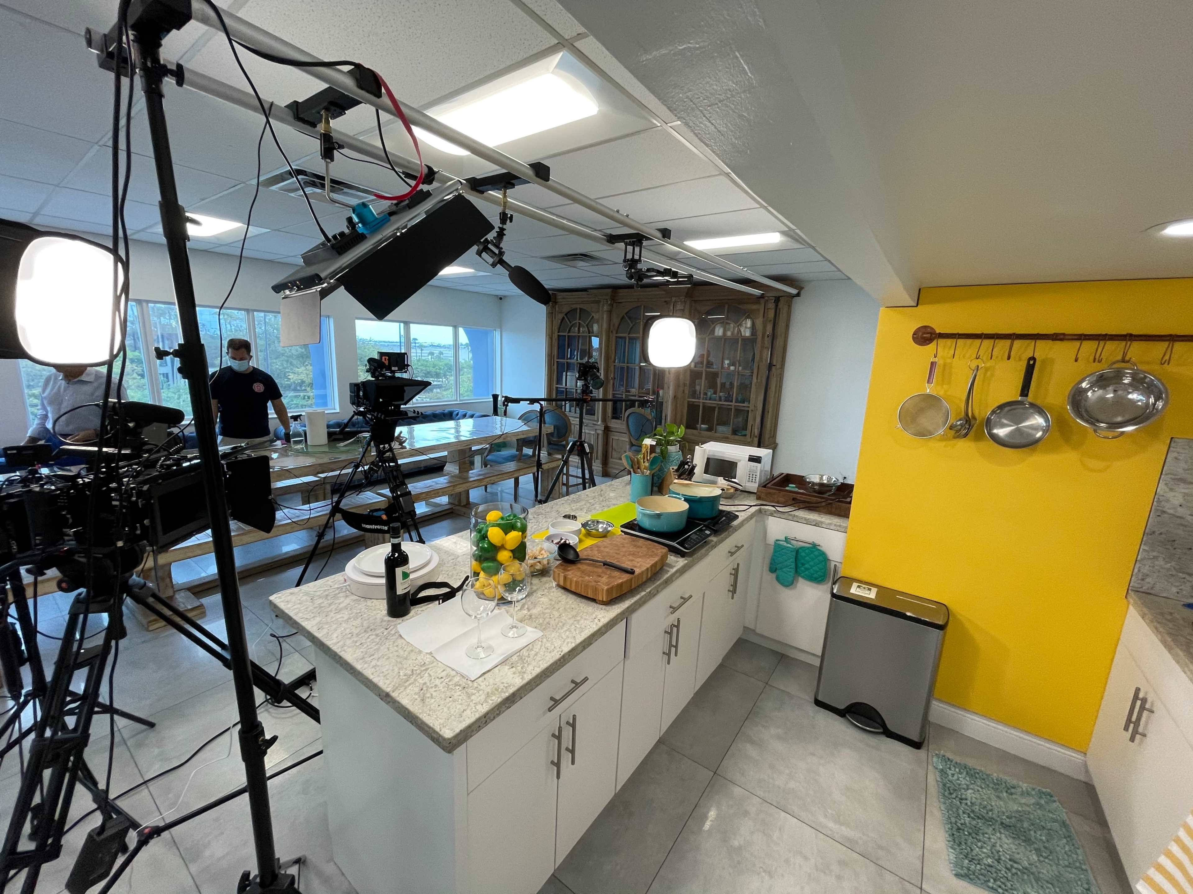 A well-equipped kitchen set for a filming project, featuring cameras, lights, and various kitchen utensils on display.