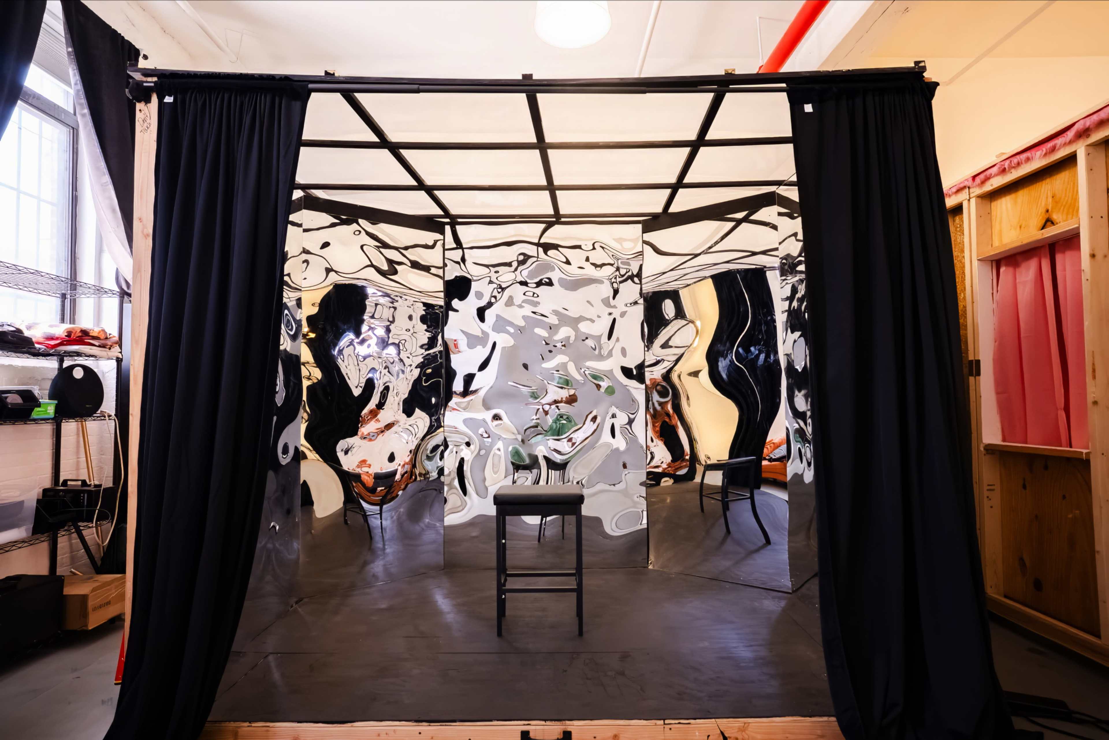 The image shows an enclosed space with mirrored walls and a single black chair in the center on a dark floor.
