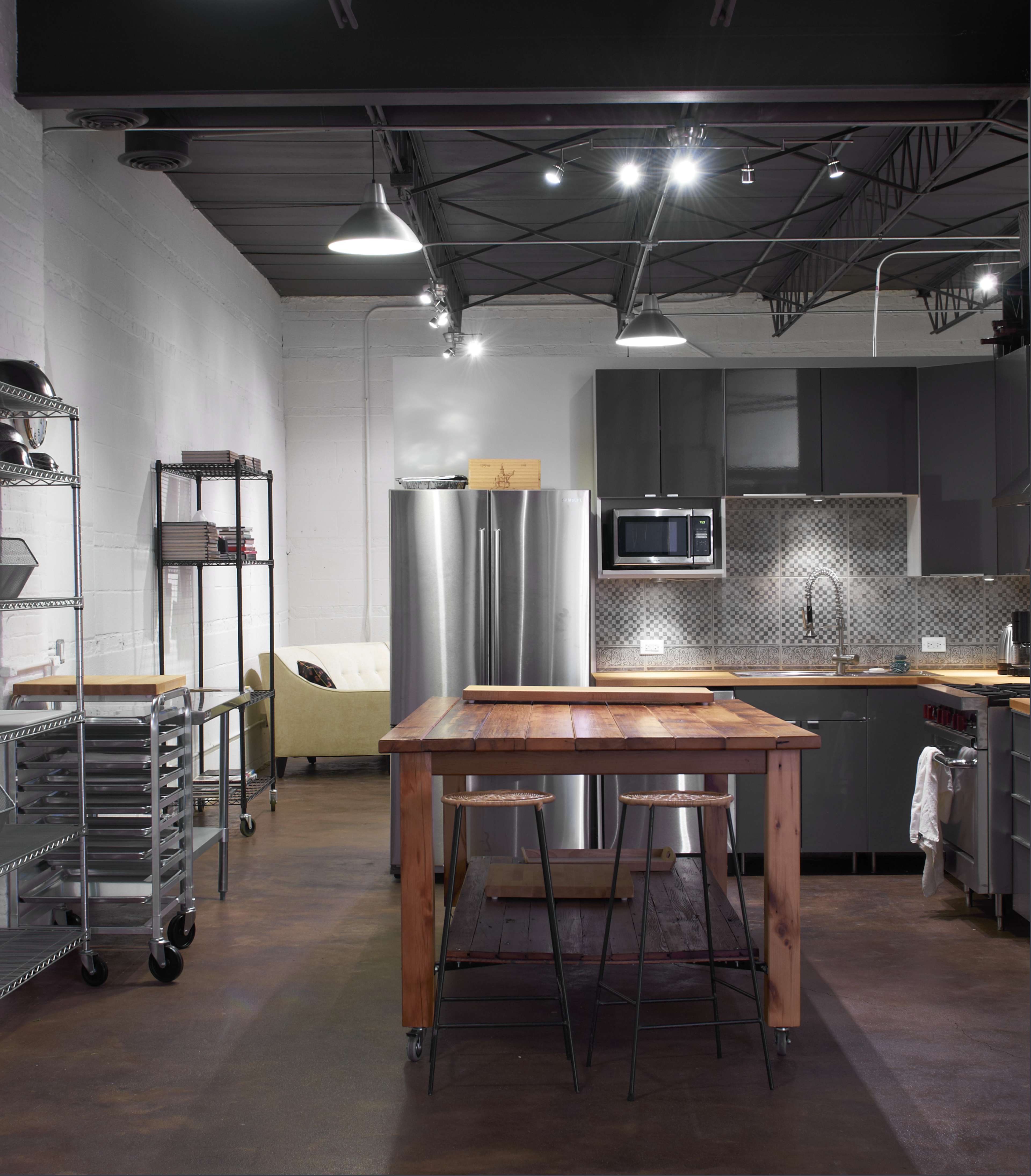 A modern kitchen with stainless steel appliances, a wooden island, and industrial-style shelving.