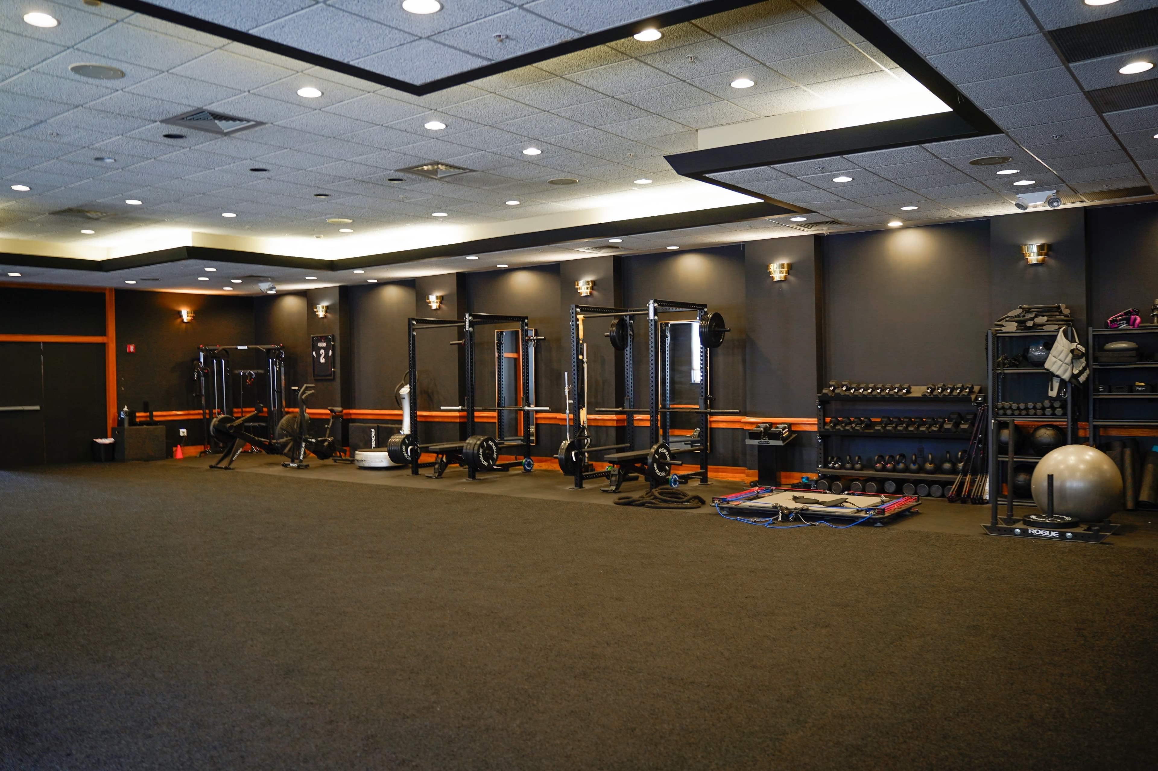A fitness facility features various weightlifting and conditioning equipment arranged along the walls.