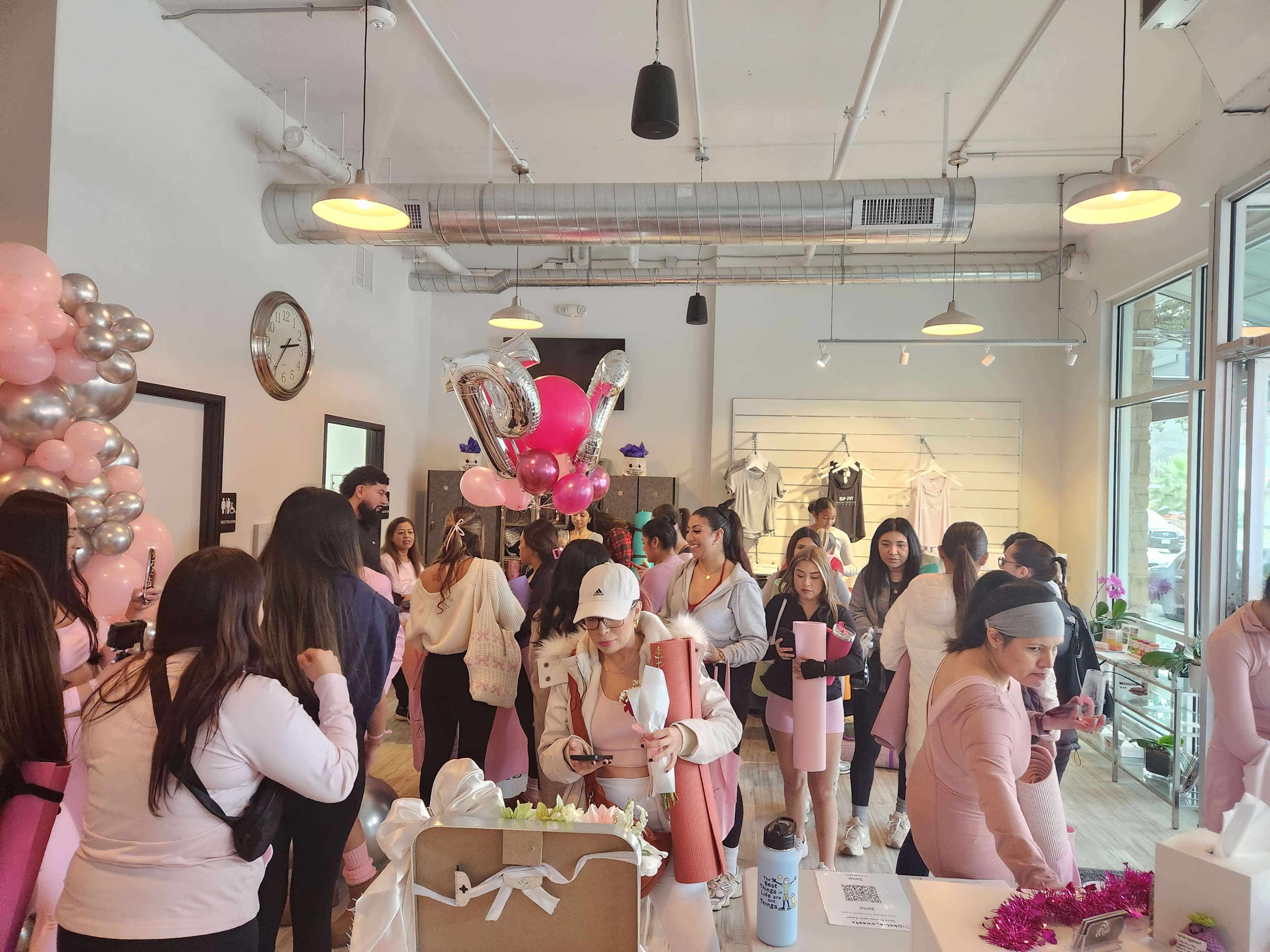 A crowded retail space features numerous shoppers mingling among decorative balloons and merchandise displays.