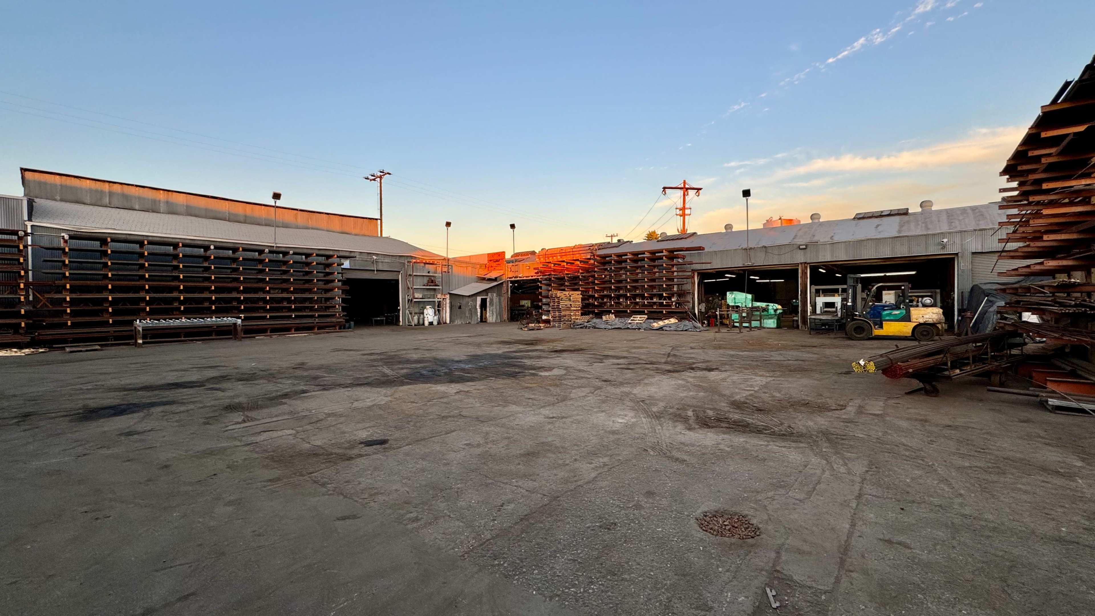 The image shows an industrial storage area with large stacks of materials organized along the walls and a forklift parked nearby.