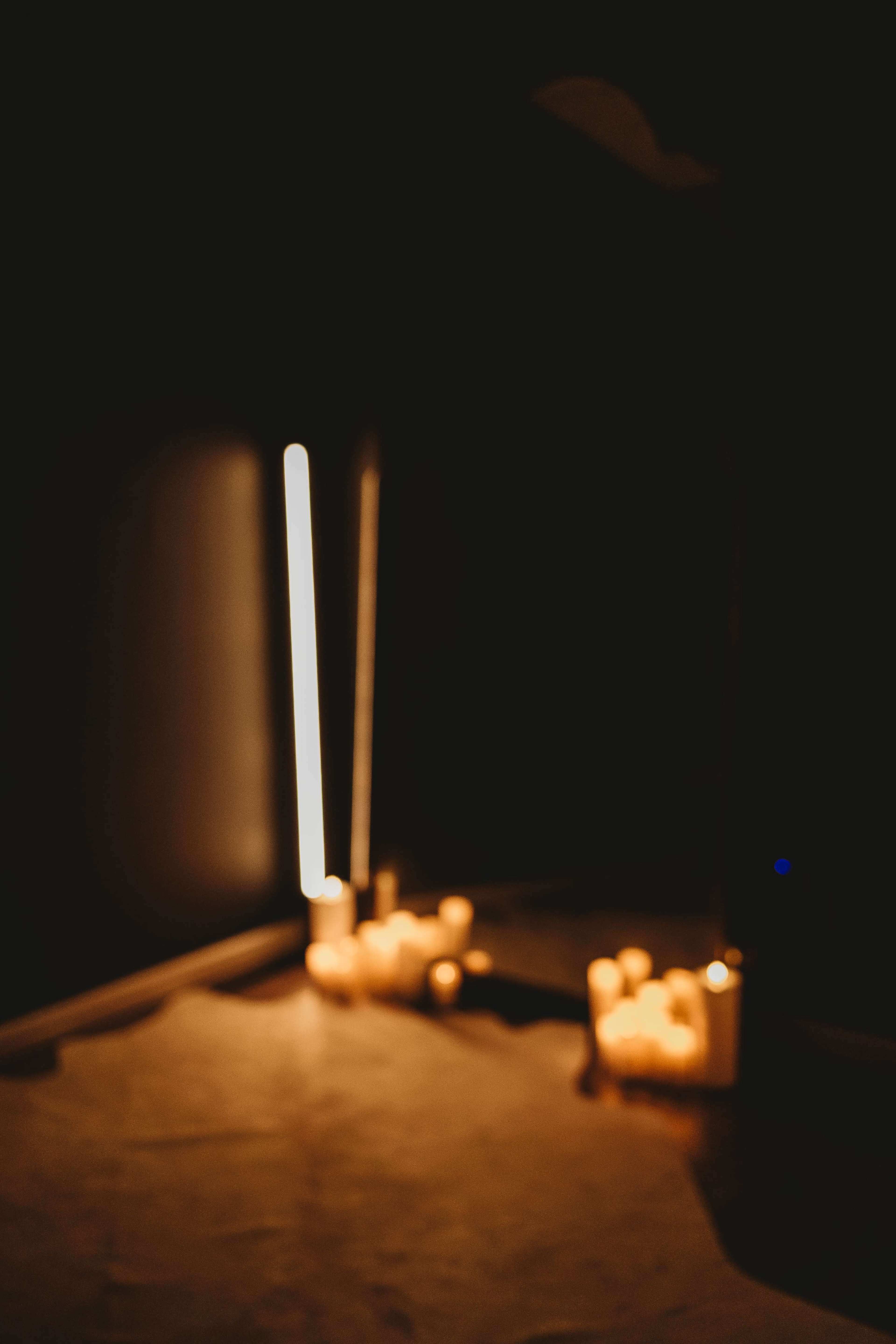 The image shows a dimly lit room with a mirror reflecting several candles arranged on the floor.