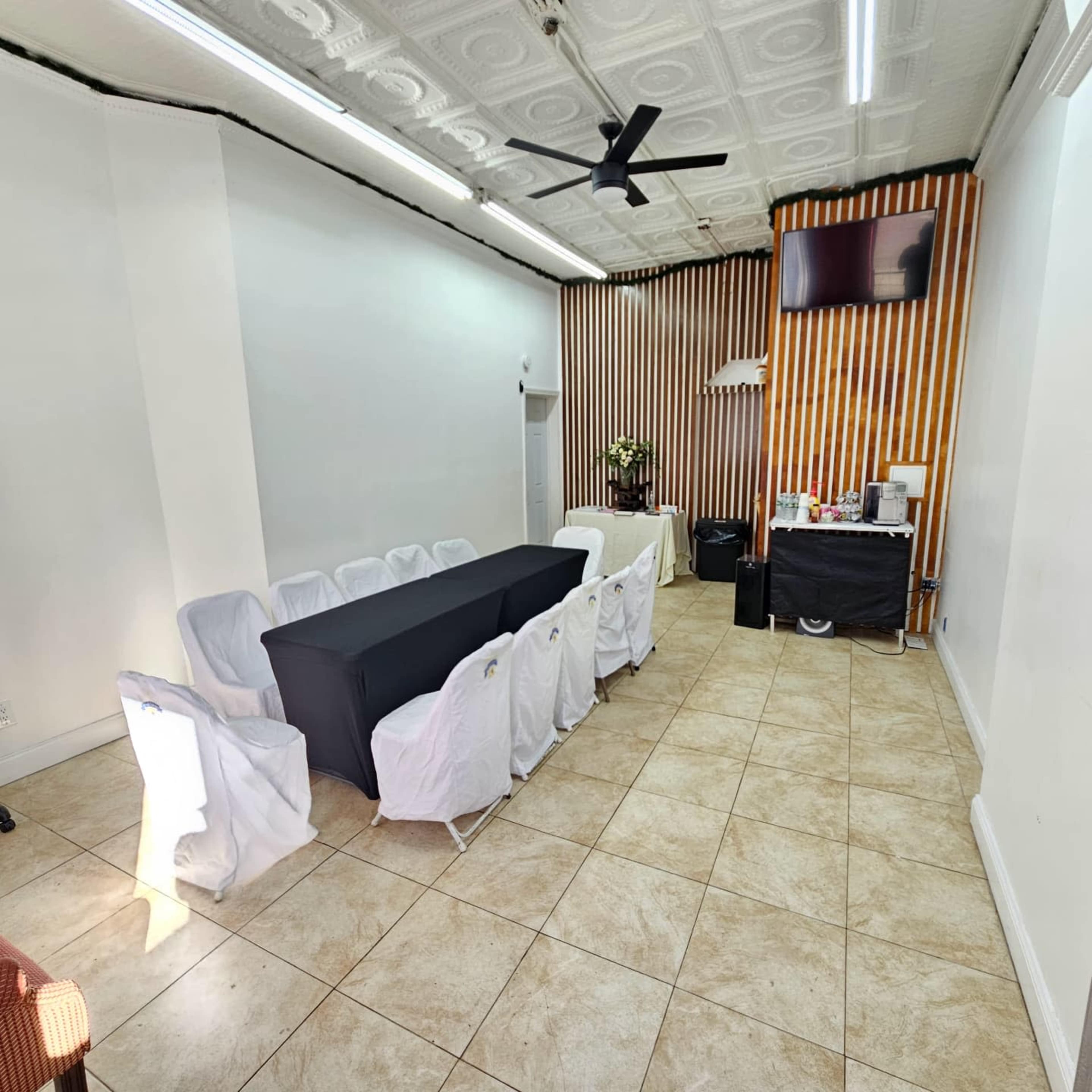 The image depicts a spacious meeting room with a long black table surrounded by white chairs, and a wall featuring vertical orange and brown stripes.