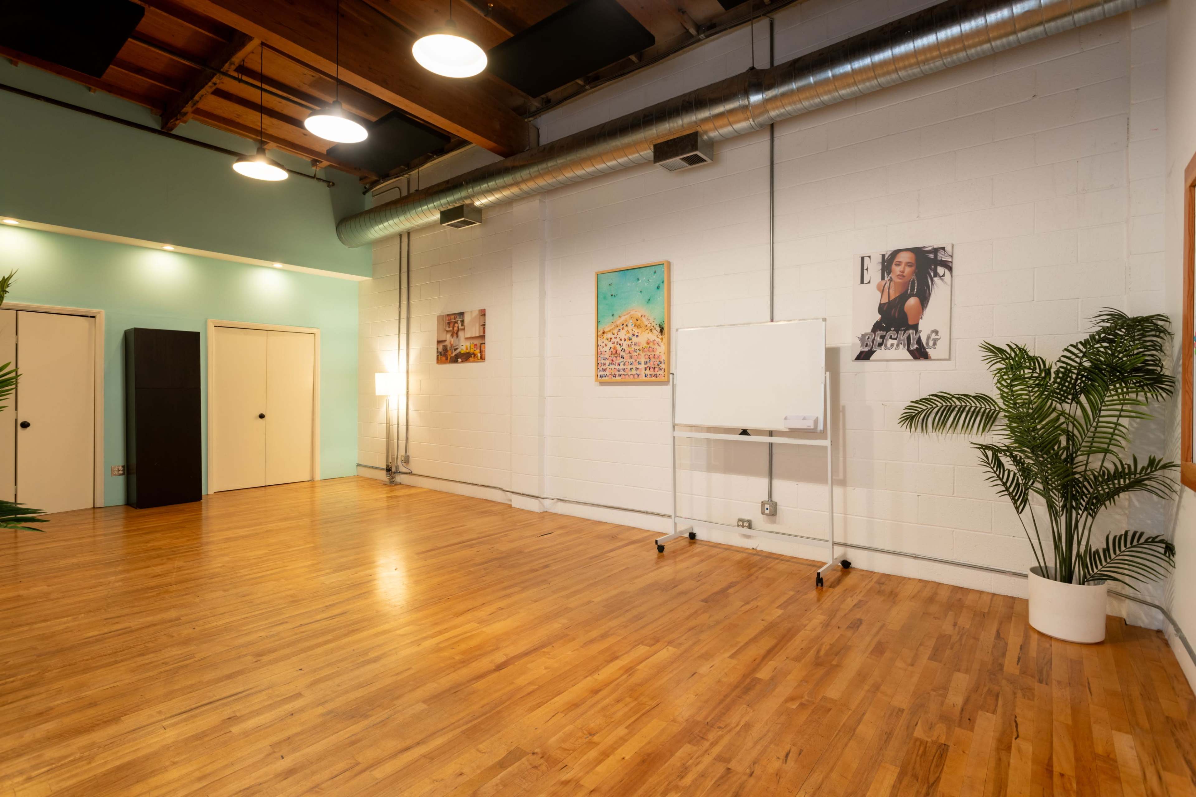 A spacious, well-lit interior with wooden flooring, featuring a whiteboard and several framed artworks on the walls.
