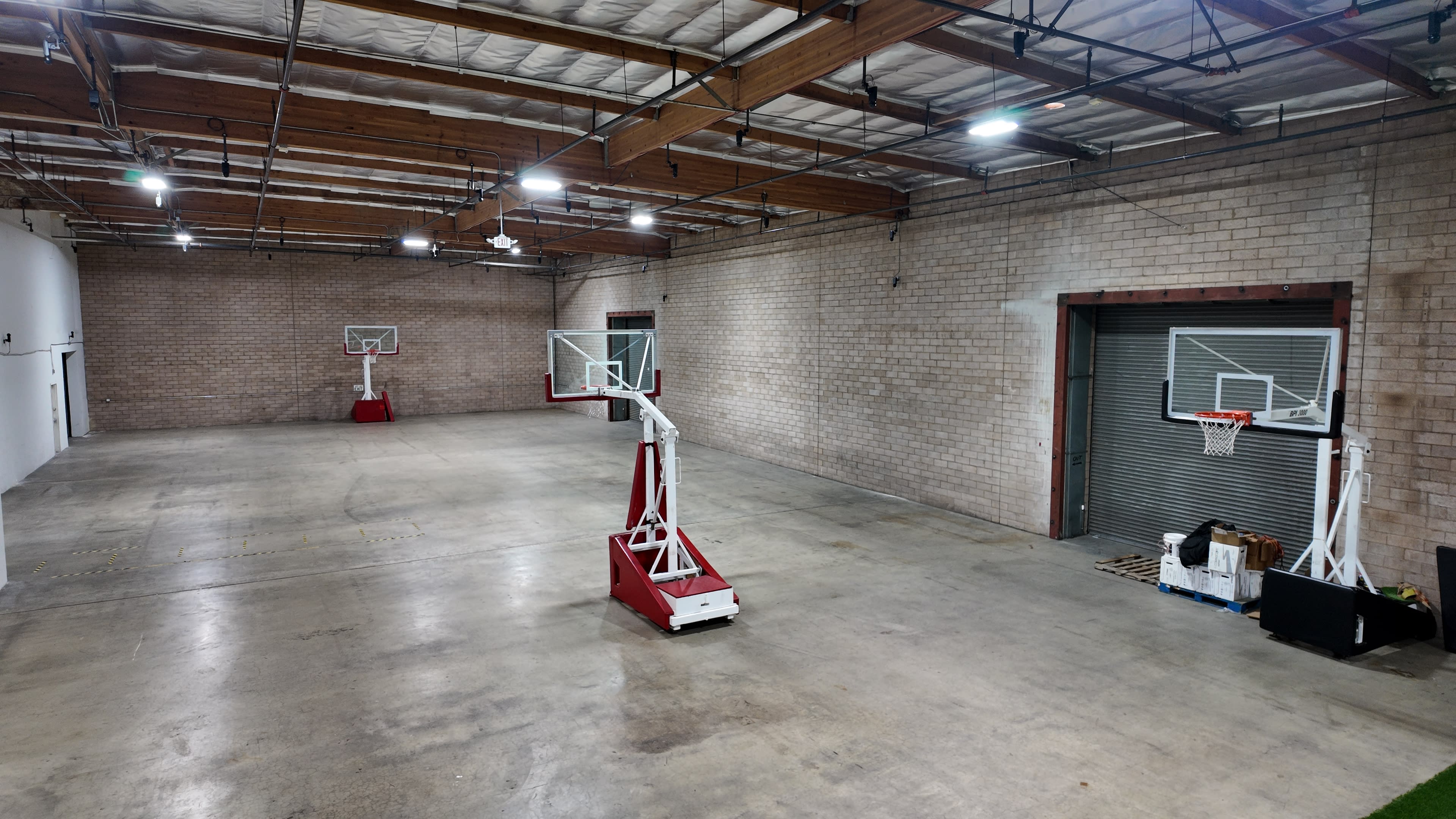 The image shows a spacious indoor basketball court with two basketball hoops positioned at opposite ends.