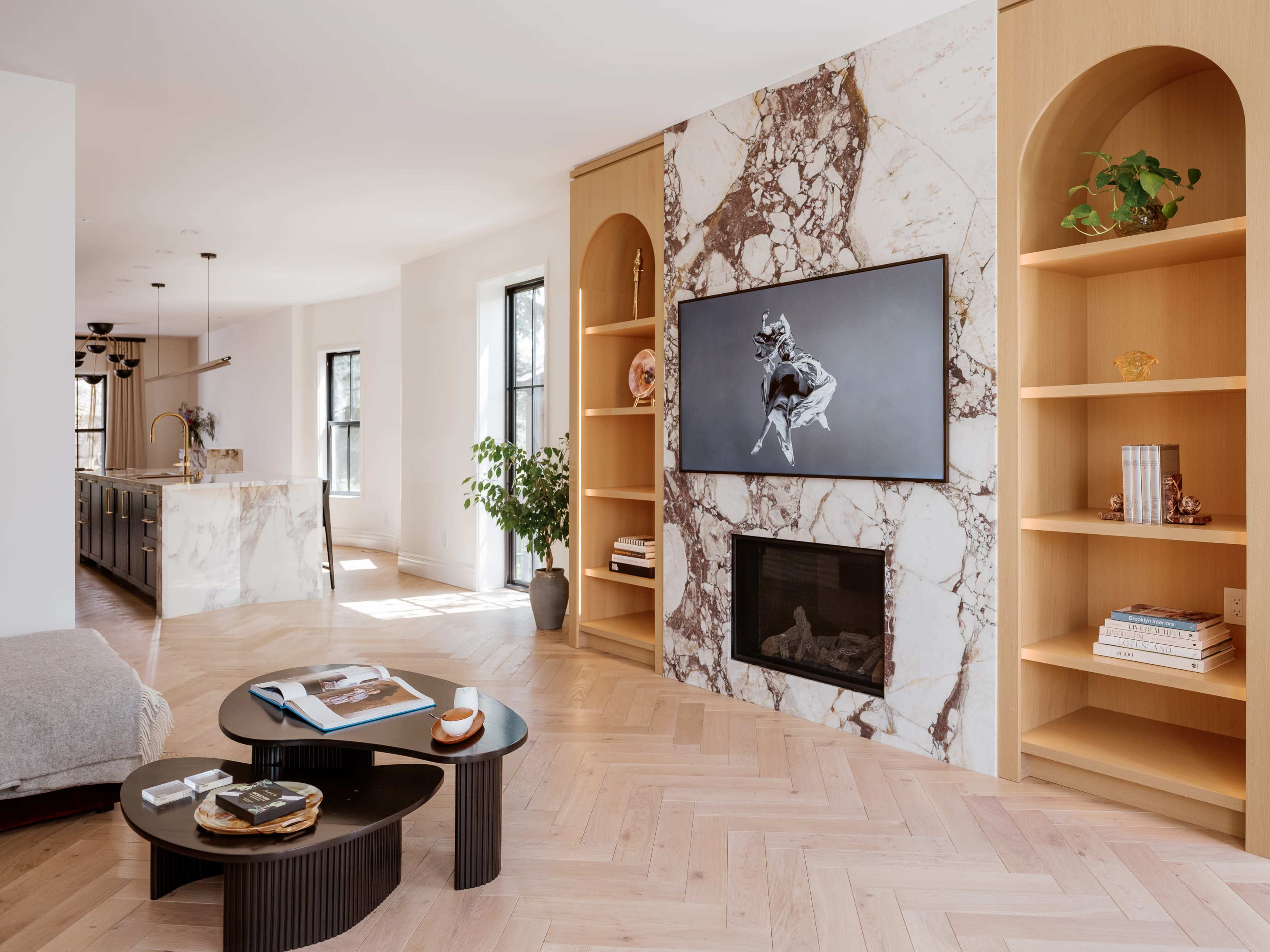 The living room features a marble accent wall with a mounted television, a modern coffee table, and built-in shelves on either side, creating a stylish and functional space.