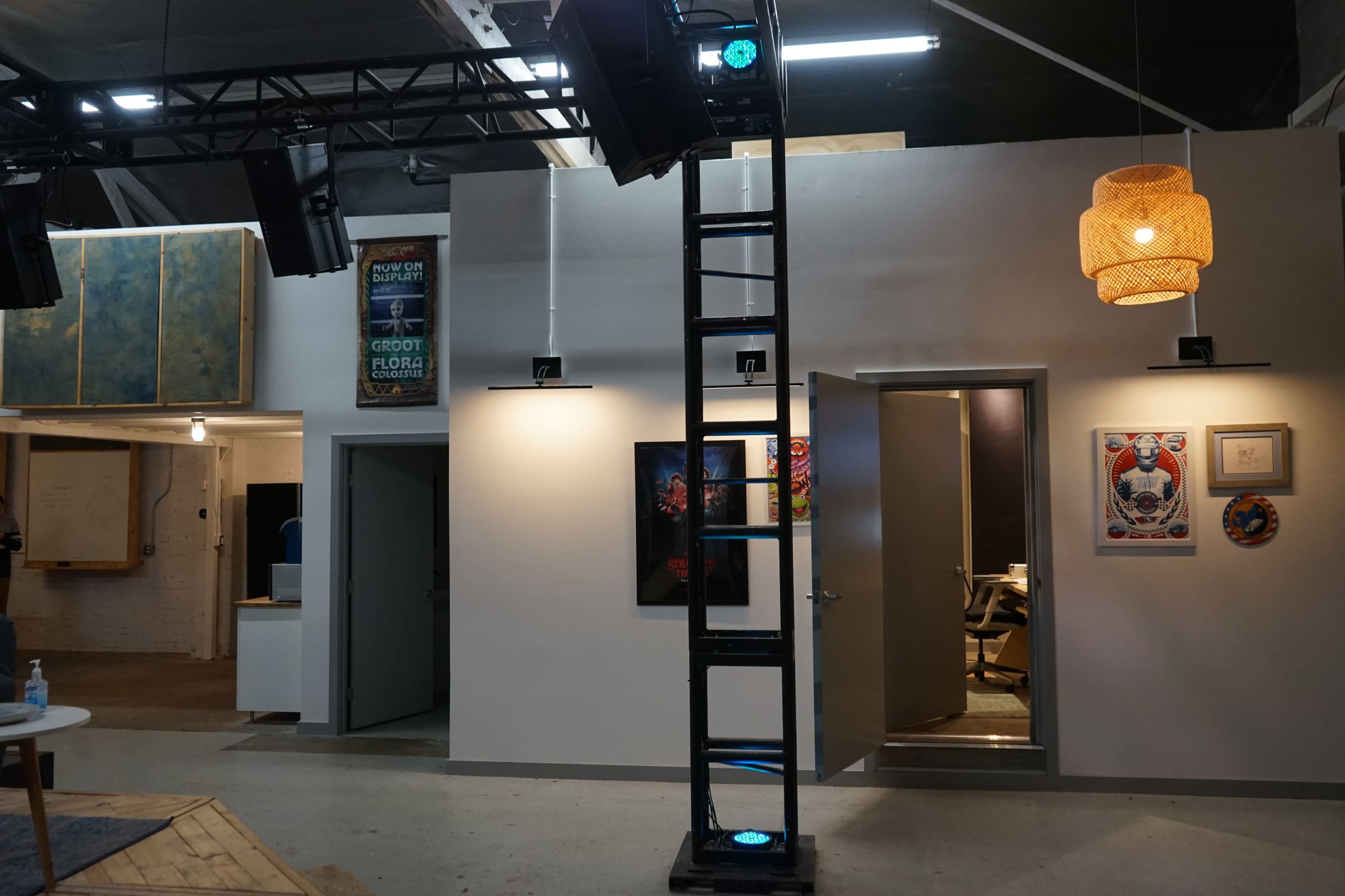 A modern workspace featuring a ladder, artwork on the walls, and partitions separating different areas.