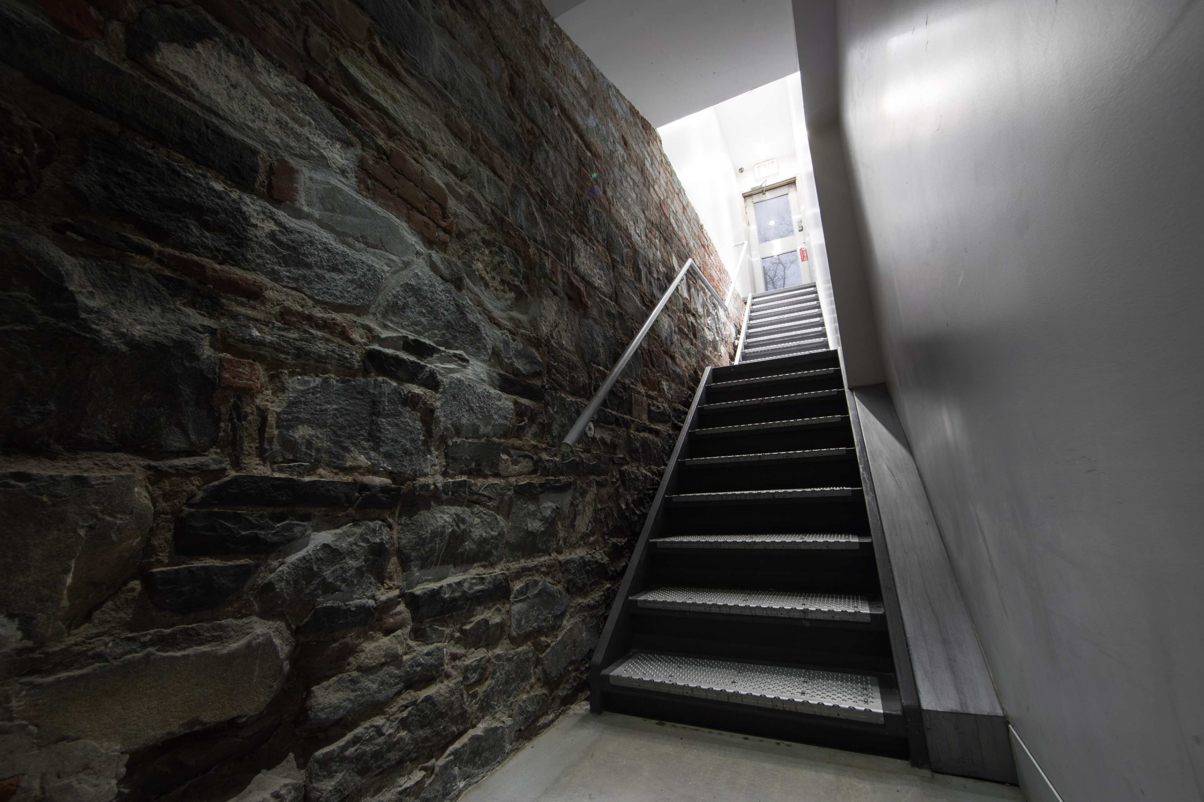 A stone-walled stairway leads upward to a door at the top.