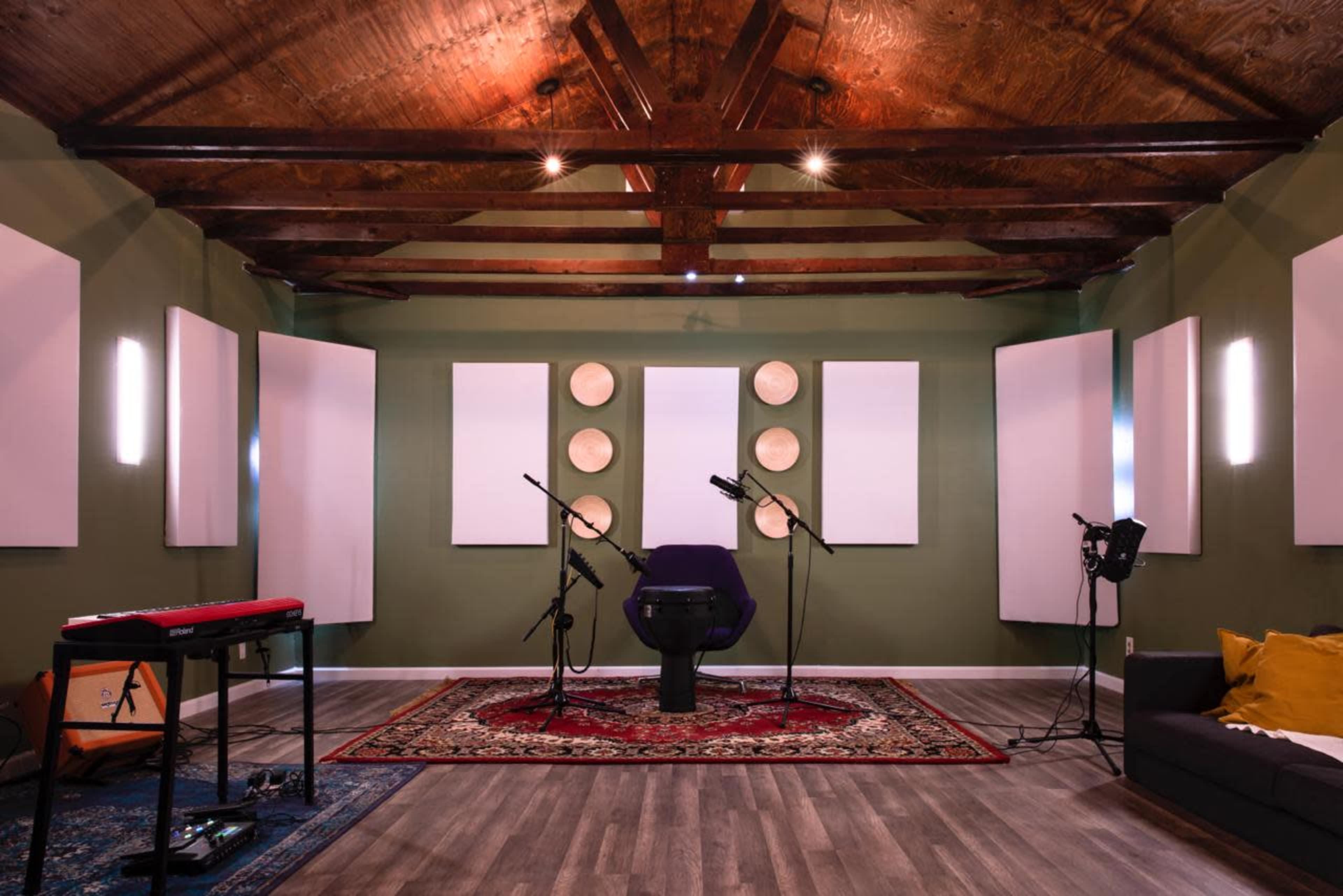 A sound studio with a purple chair, microphones, acoustic panels on the walls, and a keyboard in the foreground.