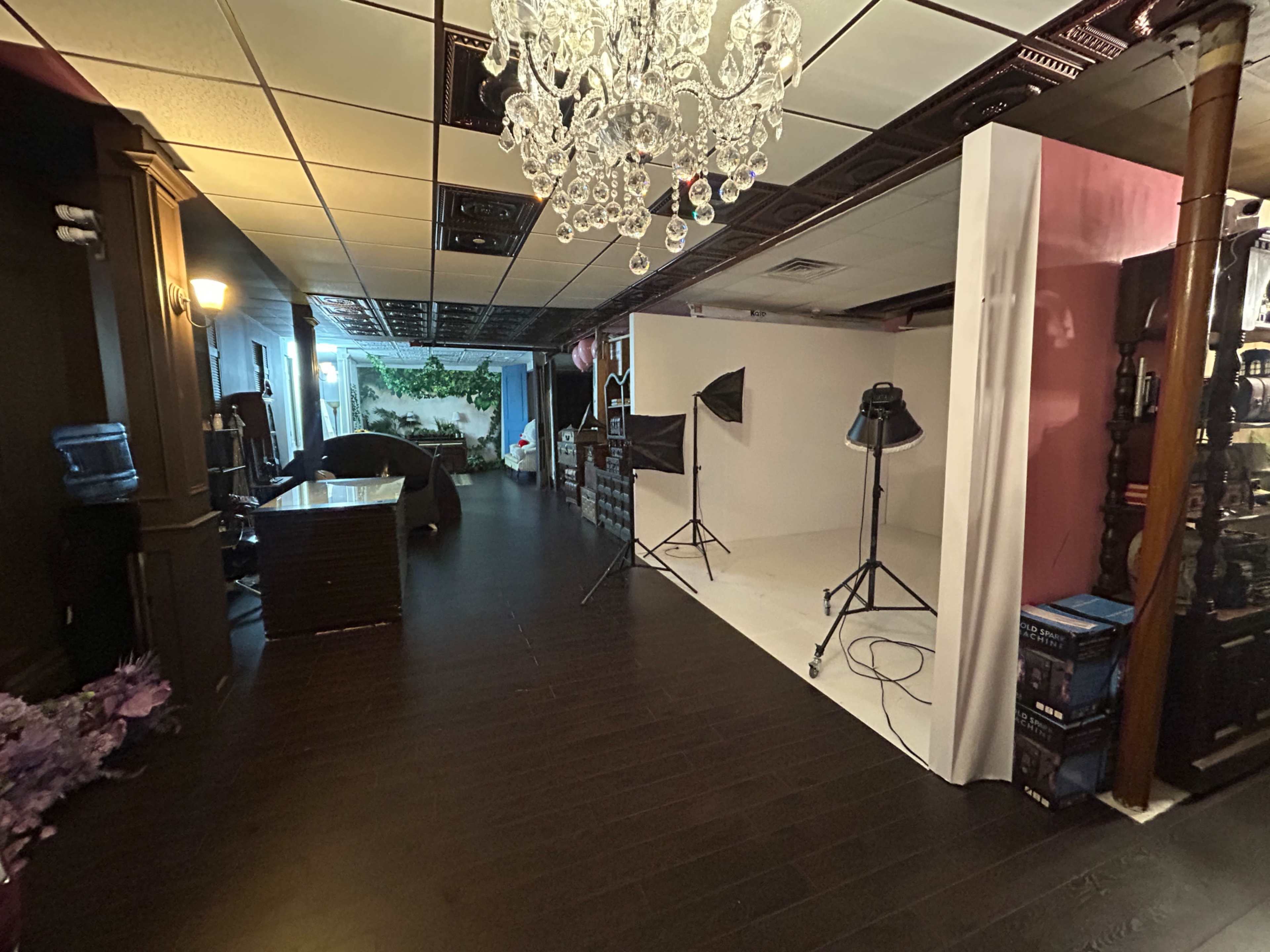 The image shows a Photography studio with a white backdrop, studio lights, a water cooler, and decorative elements along the walls.