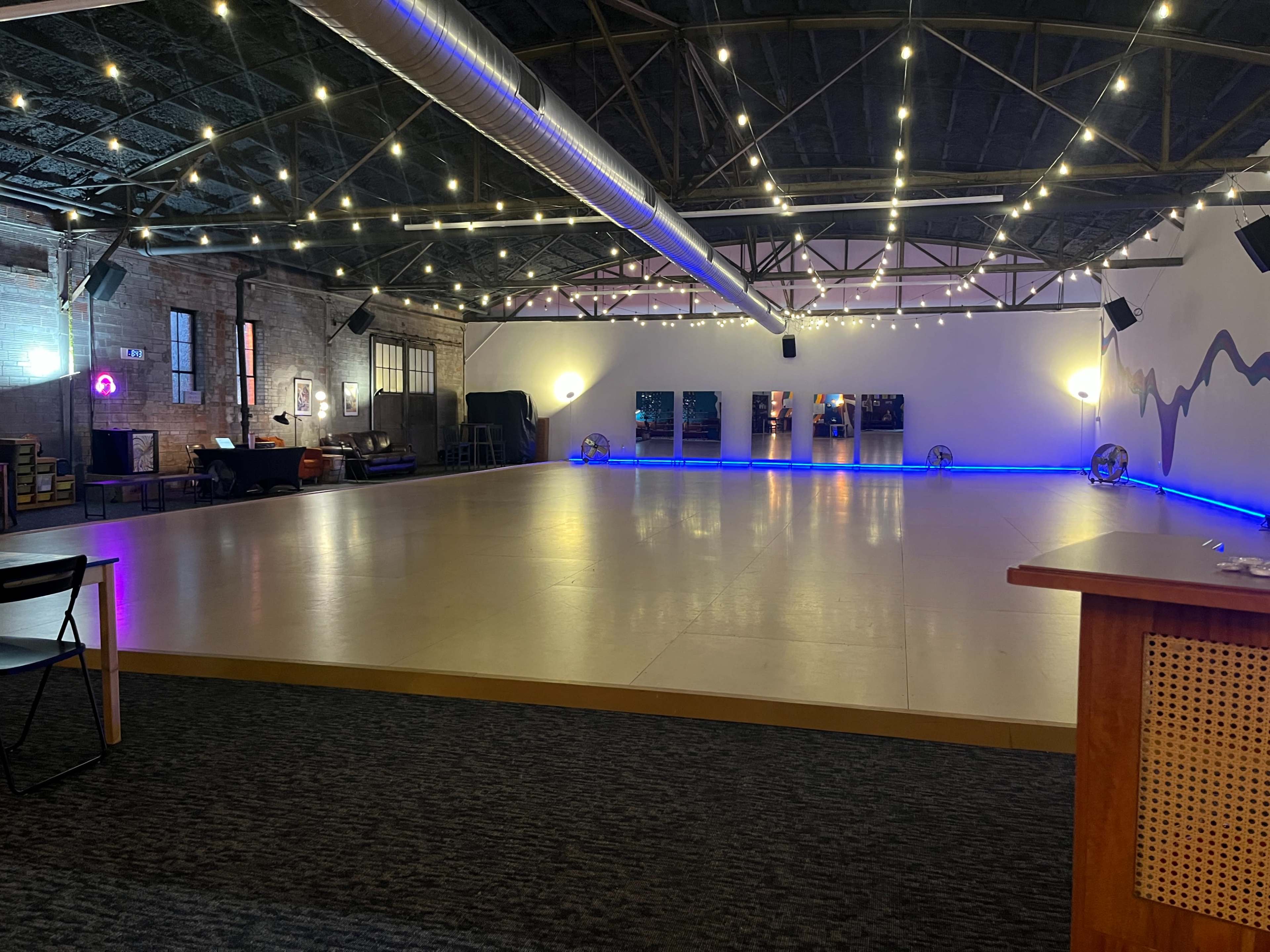 The image shows a spacious indoor area with a polished floor, ambient lighting, and a minimalist decoration scheme featuring a wall with colorful accents.