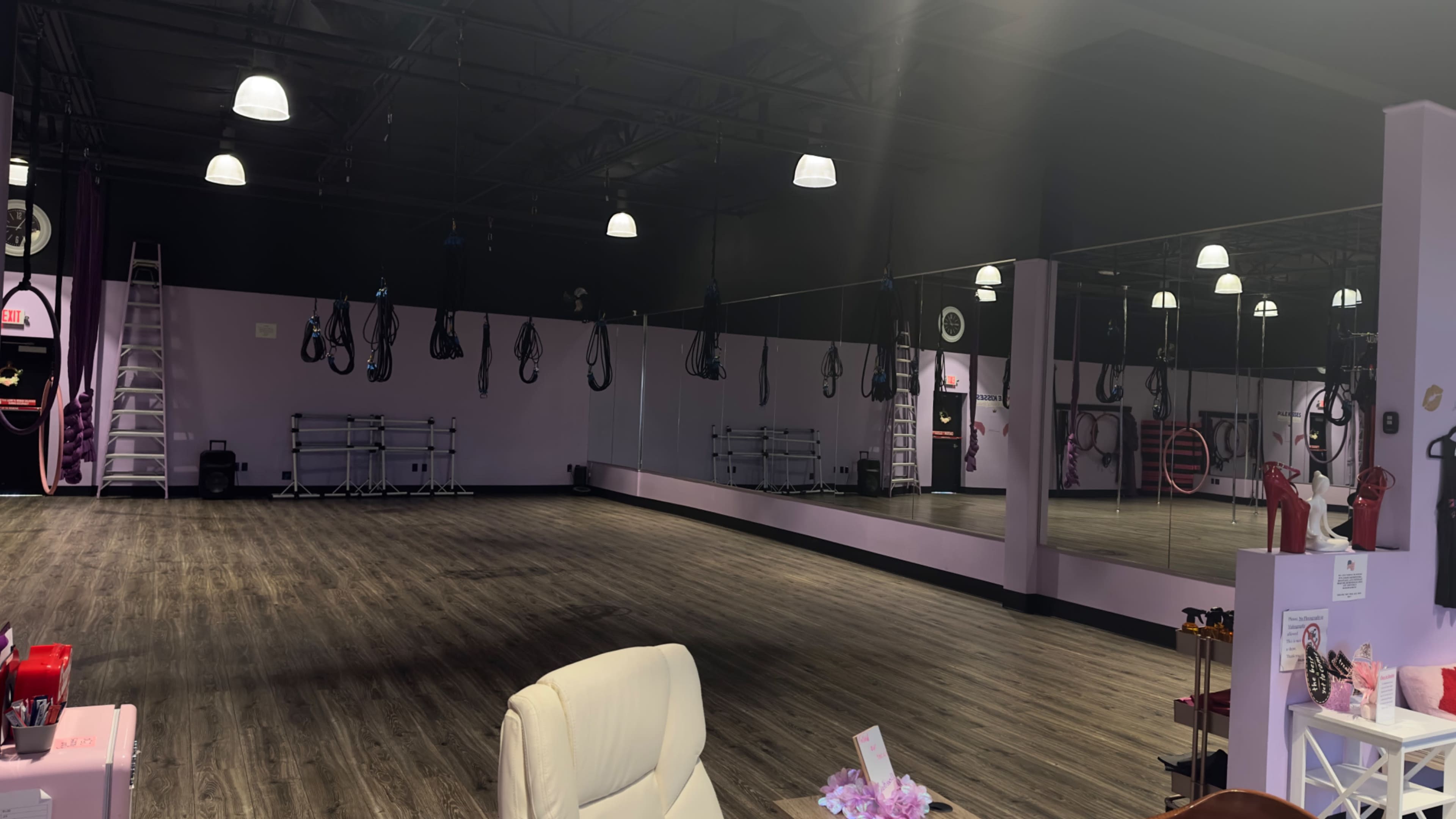 An empty studio with wooden floors, mirrored walls, and suspended equipment hanging from the ceiling.