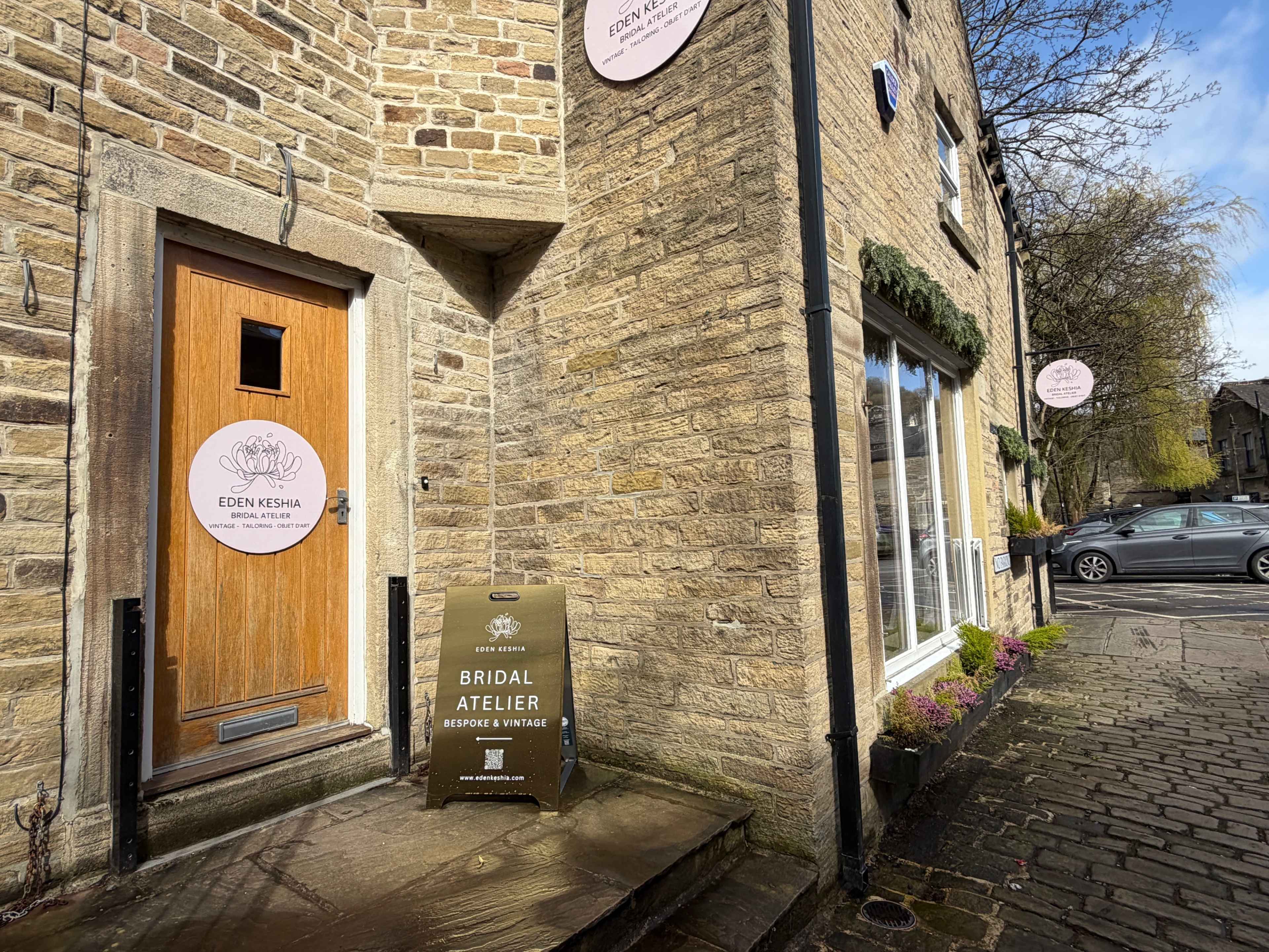 The image shows the entrance of a bridal atelier named "Eden Kesha," featuring a wooden door, stone walls, and signage outside the shop.
