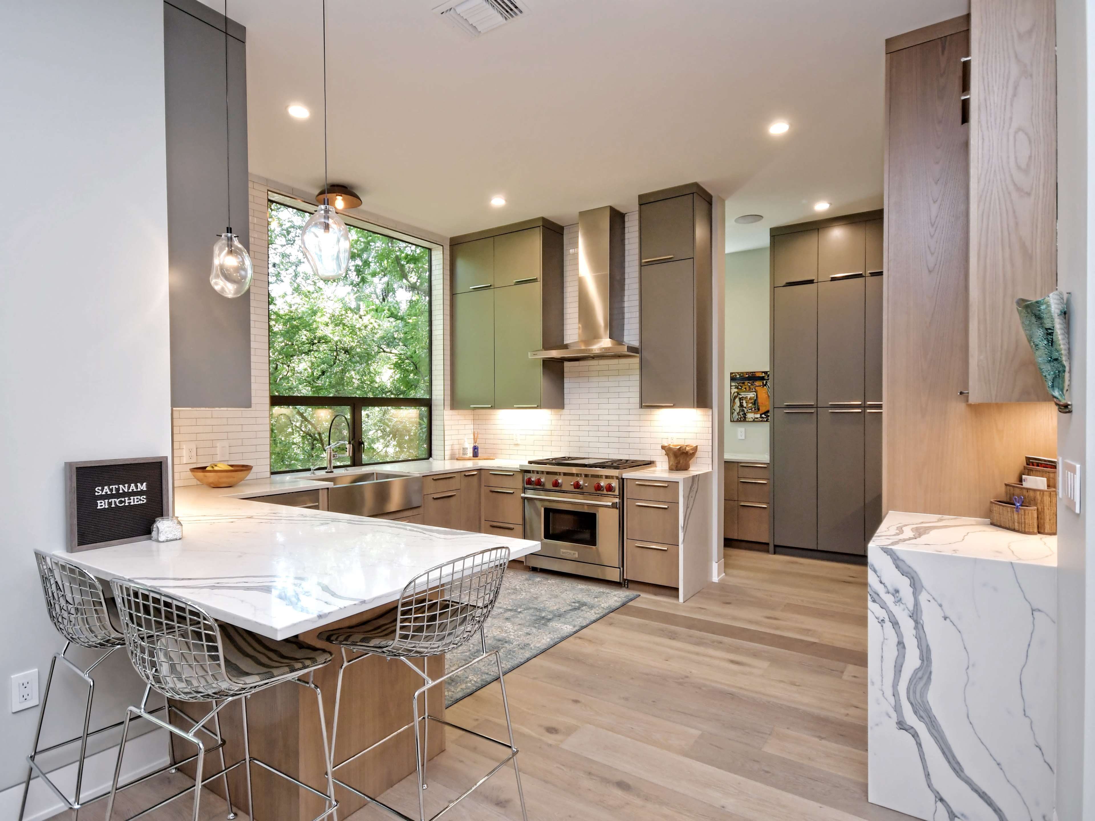 The kitchen features modern cabinetry, a large island with bar seating, and a window providing natural light.