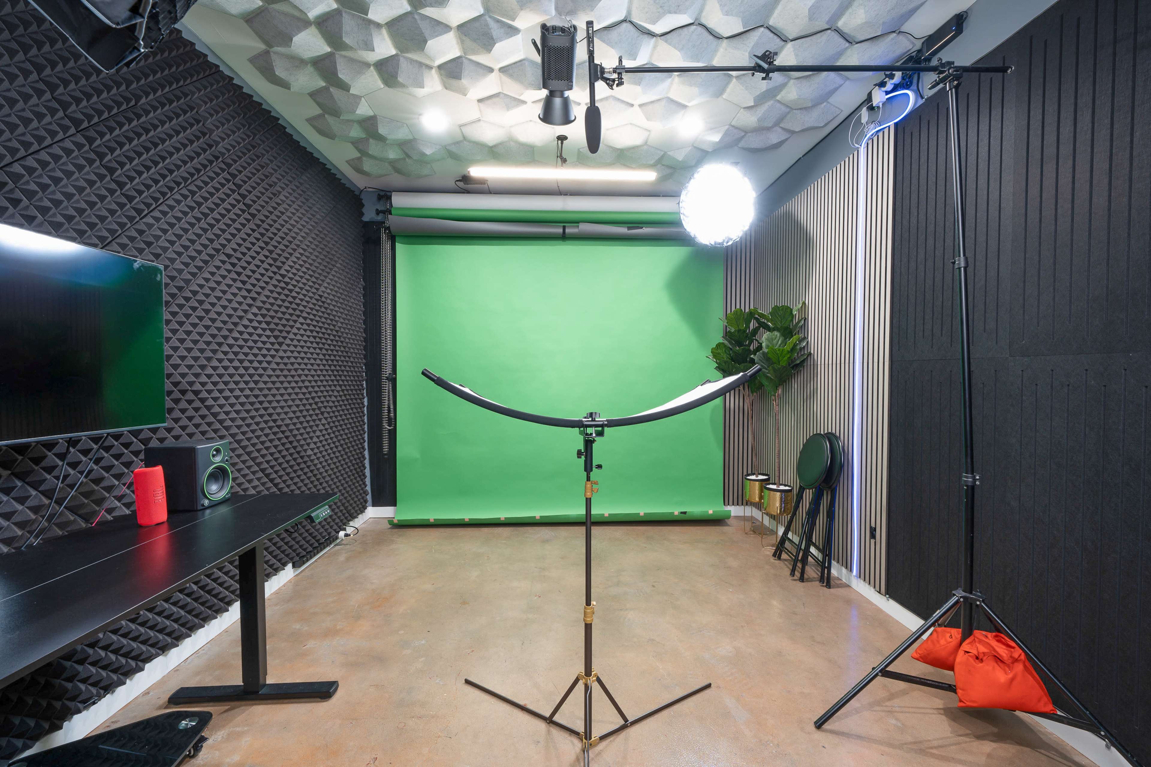 The image shows a photography studio equipped with a green backdrop, lighting equipment, and soundproofing panels on the walls.