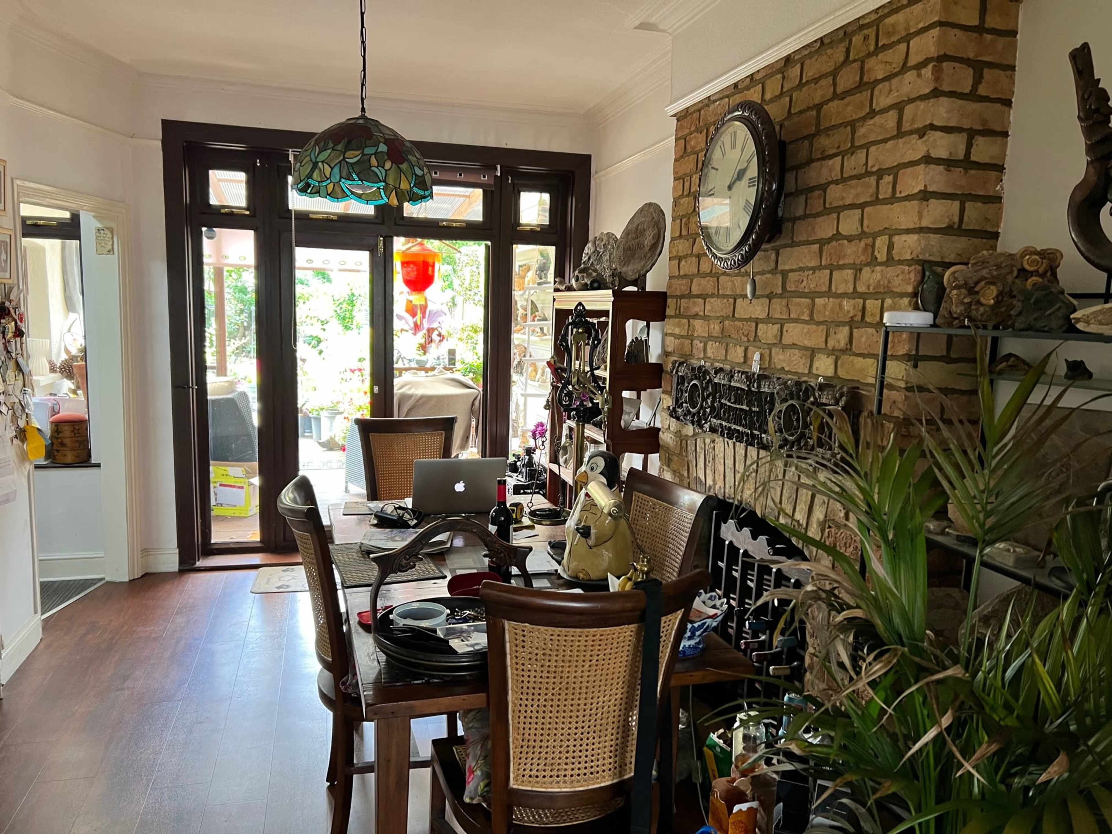 A dining area with a wooden table set for meals, a decorative brick wall, and large windows leading to an outdoor space.
