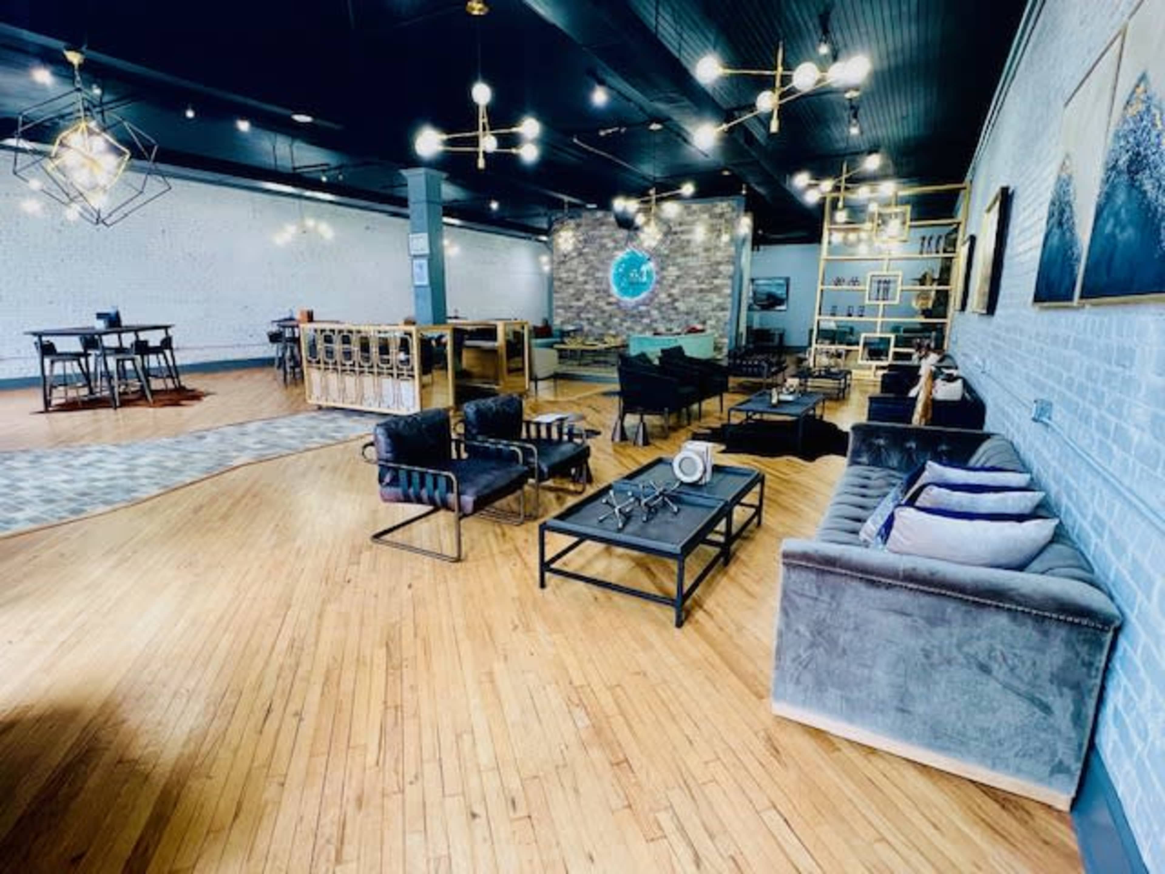 A modern, spacious interior featuring various seating areas with sofas and tables, hardwood flooring, and decorative lighting.