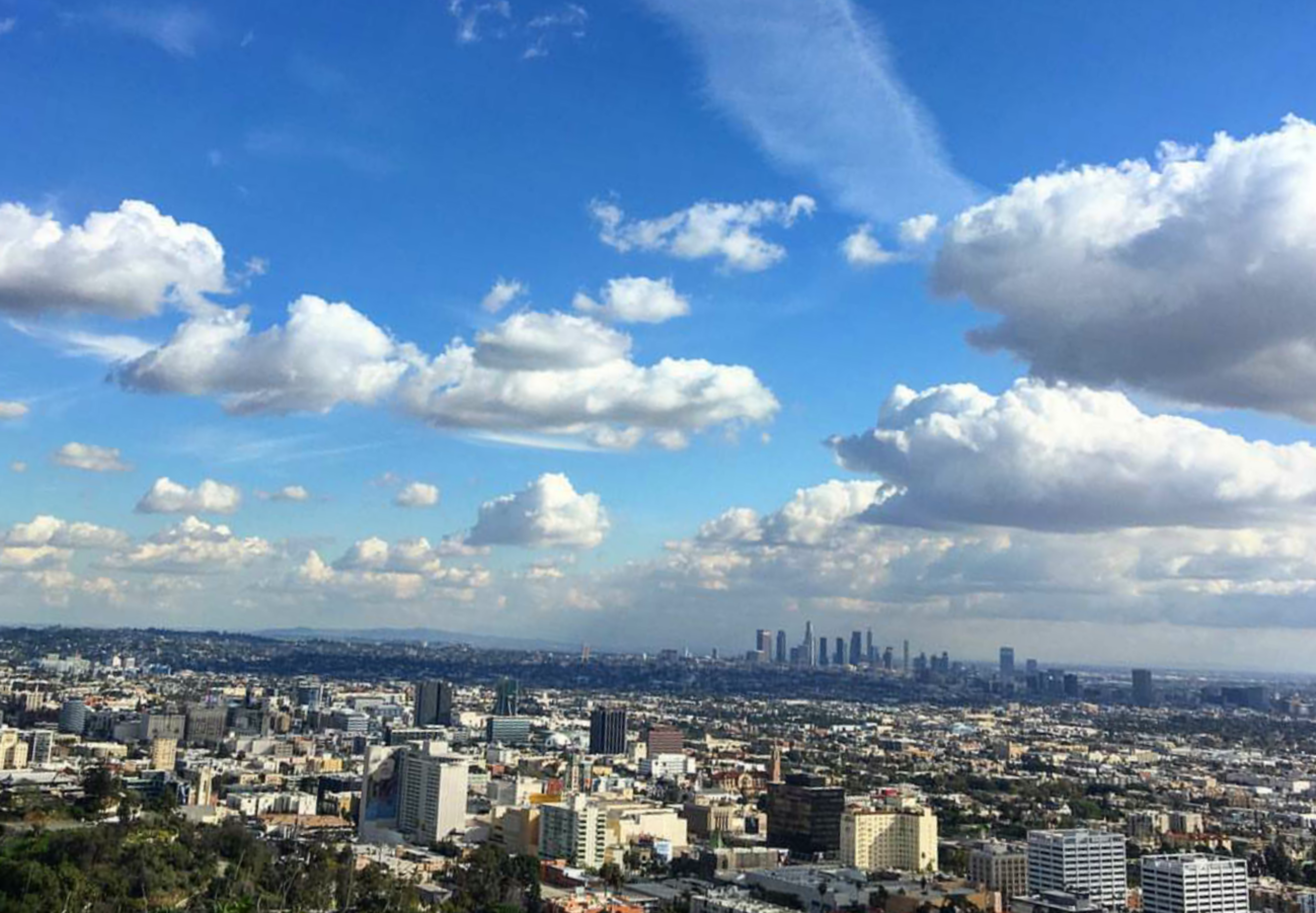 A panoramic view of a city skyline under a partly cloudy blue sky.