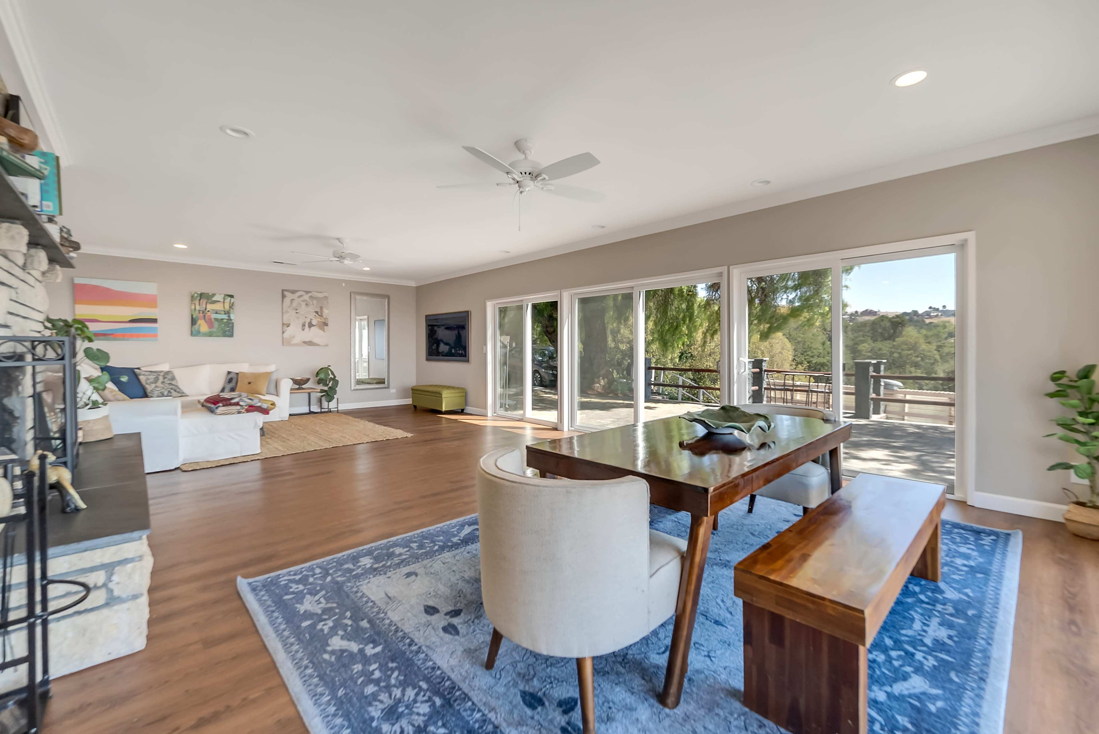 An open living area with a wooden dining table and chairs, large windows providing a view, and a comfortable seating arrangement.